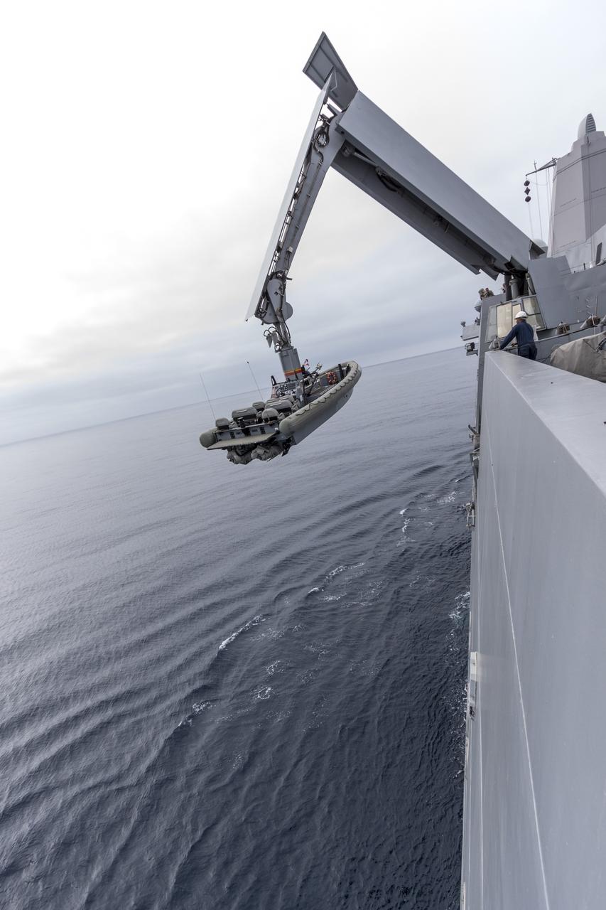 SAN DIEGO, Calif. – The USS San Diego heads out to sea with the Orion boilerplate test vehicle and other hardware in its well deck for an underway recovery test. A crane is used to lower a rigid hull inflatable boat into the water. About 100 miles offshore, NASA and the U.S. Navy conducted tests to prepare for recovery of the Orion crew module, forward bay cover and parachutes on its return from a deep space mission. The underway recovery test will allow the teams to demonstrate and evaluate the recovery processes, procedures, hardware and personnel in open waters. During the testing, the tether lines were unable to support the tension caused by crew module motion that was driven by wave turbulence in the well deck of the ship. NASA and the U.S. Navy are reviewing the testing data collected to evaluate the next steps. The Ground Systems Development and Operations Program conducted the underway recovery tests. Orion is the exploration spacecraft designed to carry astronauts to destinations not yet explored by humans, including an asteroid and Mars. It will have emergency abort capability, sustain the crew during space travel and provide safe re-entry from deep space return velocities. The first unpiloted test flight of the Orion is scheduled to launch in 2014 atop a Delta IV rocket and in 2017 on NASA’s Space Launch System rocket. For more information, visit http://www.nasa.gov/orion. Photo credit: NASA/Cory Huston