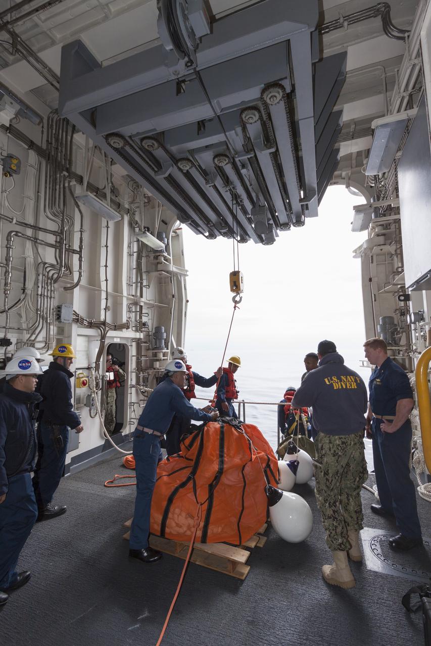 SAN DIEGO, Calif. – In the well deck of the USS San Diego, NASA and U.S. Navy personnel prepare a parachute for transfer into the water as part of the Orion underway recovery test. The Orion boilerplate test vehicle and other hardware are secured in the well deck of the ship in preparation for the test about 100 miles off the coast of San Diego, California. NASA and the U.S. Navy conducted tests to prepare for the recovery of the Orion crew module, forward bay cover and parachutes on its return from a deep space mission. The underway recovery test will allow the teams to demonstrate and evaluate the recovery processes, procedures, hardware and personnel in open waters. During the testing, the tether lines were unable to support the tension caused by crew module motion that was driven by wave turbulence in the well deck of the ship. NASA and the U.S. Navy are reviewing the testing data collected to evaluate the next steps. The Ground Systems Development and Operations Program conducted the underway recovery tests. Orion is the exploration spacecraft designed to carry astronauts to destinations not yet explored by humans, including an asteroid and Mars. It will have emergency abort capability, sustain the crew during space travel and provide safe re-entry from deep space return velocities. The first unpiloted test flight of the Orion is scheduled to launch in 2014 atop a Delta IV rocket and in 2017 on NASA’s Space Launch System rocket. For more information, visit http://www.nasa.gov/orion. Photo credit: NASA/Cory Huston  