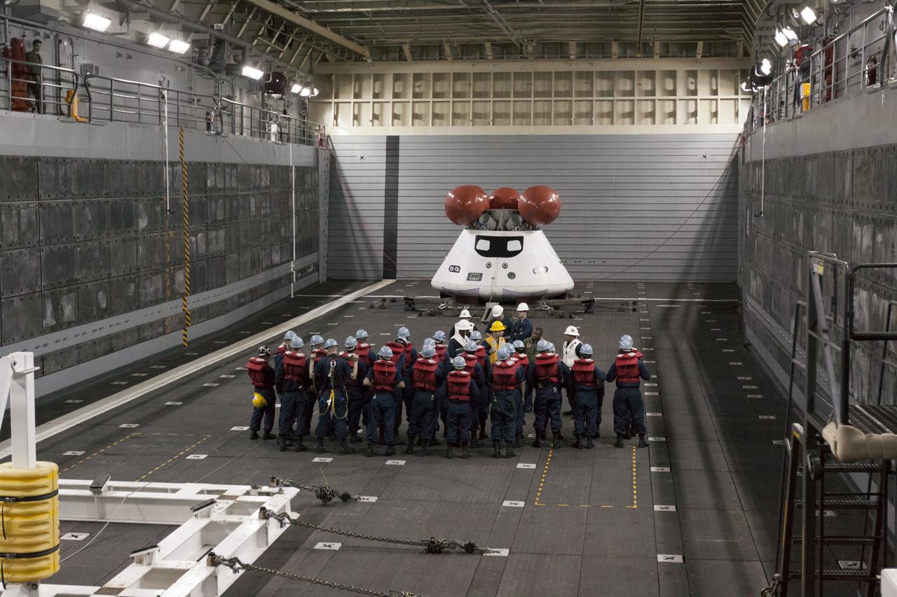 SAN DIEGO, Calif. – In the well deck of the USS San Diego, NASA and U.S. Navy personnel gather near the Orion boilerplate test article and other hardware before the underway recovery test begins in the Pacific Ocean, about 100 miles off the coast of San Diego, California. NASA and the U.S. Navy conducted tests to prepare for the recovery of the Orion crew module, forward bay cover and parachutes on its return from a deep space mission. The underway recovery test will allow the teams to demonstrate and evaluate the recovery processes, procedures, hardware and personnel in open waters. During the testing, the tether lines were unable to support the tension caused by crew module motion that was driven by wave turbulence in the well deck of the ship. NASA and the U.S. Navy are reviewing the testing data collected to evaluate the next steps. The Ground Systems Development and Operations Program conducted the underway recovery tests. Orion is the exploration spacecraft designed to carry astronauts to destinations not yet explored by humans, including an asteroid and Mars. It will have emergency abort capability, sustain the crew during space travel and provide safe re-entry from deep space return velocities. The first unpiloted test flight of the Orion is scheduled to launch in 2014 atop a Delta IV rocket and in 2017 on NASA’s Space Launch System rocket. For more information, visit http://www.nasa.gov/orion. Photo credit: NASA/Cory Huston