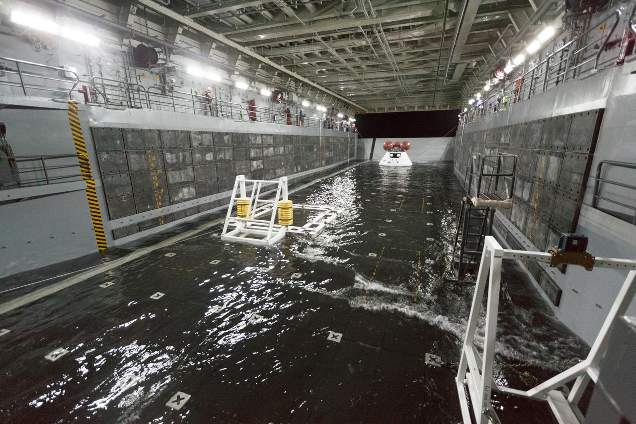 SAN DIEGO, Calif. – The well deck of the USS San Diego fills with water and surrounds the Orion boilerplate test article and other hardware as the underway recovery test begins in the Pacific Ocean, about 100 miles off the coast of San Diego, California. NASA and the U.S. Navy conducted tests to prepare for the recovery of the Orion crew module, forward bay cover and parachutes on its return from a deep space mission. The underway recovery test will allow the teams to demonstrate and evaluate the recovery processes, procedures, hardware and personnel in open waters. During the testing, the tether lines were unable to support the tension caused by crew module motion that was driven by wave turbulence in the well deck of the ship. NASA and the U.S. Navy are reviewing the testing data collected to evaluate the next steps. The Ground Systems Development and Operations Program conducted the underway recovery tests. Orion is the exploration spacecraft designed to carry astronauts to destinations not yet explored by humans, including an asteroid and Mars. It will have emergency abort capability, sustain the crew during space travel and provide safe re-entry from deep space return velocities. The first unpiloted test flight of the Orion is scheduled to launch in 2014 atop a Delta IV rocket and in 2017 on NASA’s Space Launch System rocket. For more information, visit http://www.nasa.gov/orion. Photo credit: NASA/Cory Huston  