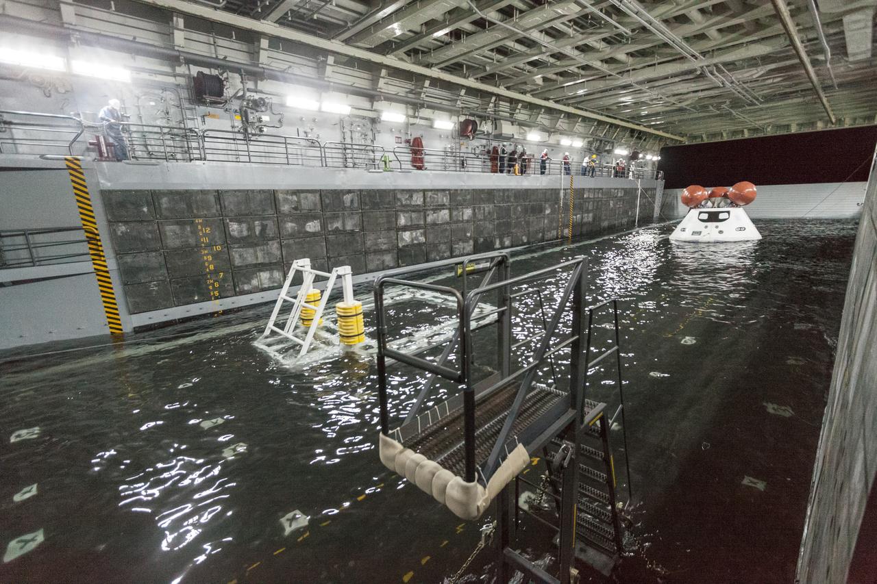 SAN DIEGO, Calif. – The well deck of the USS San Diego fills with water and surrounds the Orion boilerplate test article and other hardware as the underway recovery test begins in the Pacific Ocean, about 100 miles off the coast of San Diego, California. NASA and the U.S. Navy conducted tests to prepare for the recovery of the Orion crew module, forward bay cover and parachutes on its return from a deep space mission. The underway recovery test will allow the teams to demonstrate and evaluate the recovery processes, procedures, hardware and personnel in open waters. During the testing, the tether lines were unable to support the tension caused by crew module motion that was driven by wave turbulence in the well deck of the ship. NASA and the U.S. Navy are reviewing the testing data collected to evaluate the next steps. The Ground Systems Development and Operations Program conducted the underway recovery tests. Orion is the exploration spacecraft designed to carry astronauts to destinations not yet explored by humans, including an asteroid and Mars. It will have emergency abort capability, sustain the crew during space travel and provide safe re-entry from deep space return velocities. The first unpiloted test flight of the Orion is scheduled to launch in 2014 atop a Delta IV rocket and in 2017 on NASA’s Space Launch System rocket. For more information, visit http://www.nasa.gov/orion. Photo credit: NASA/Cory Huston