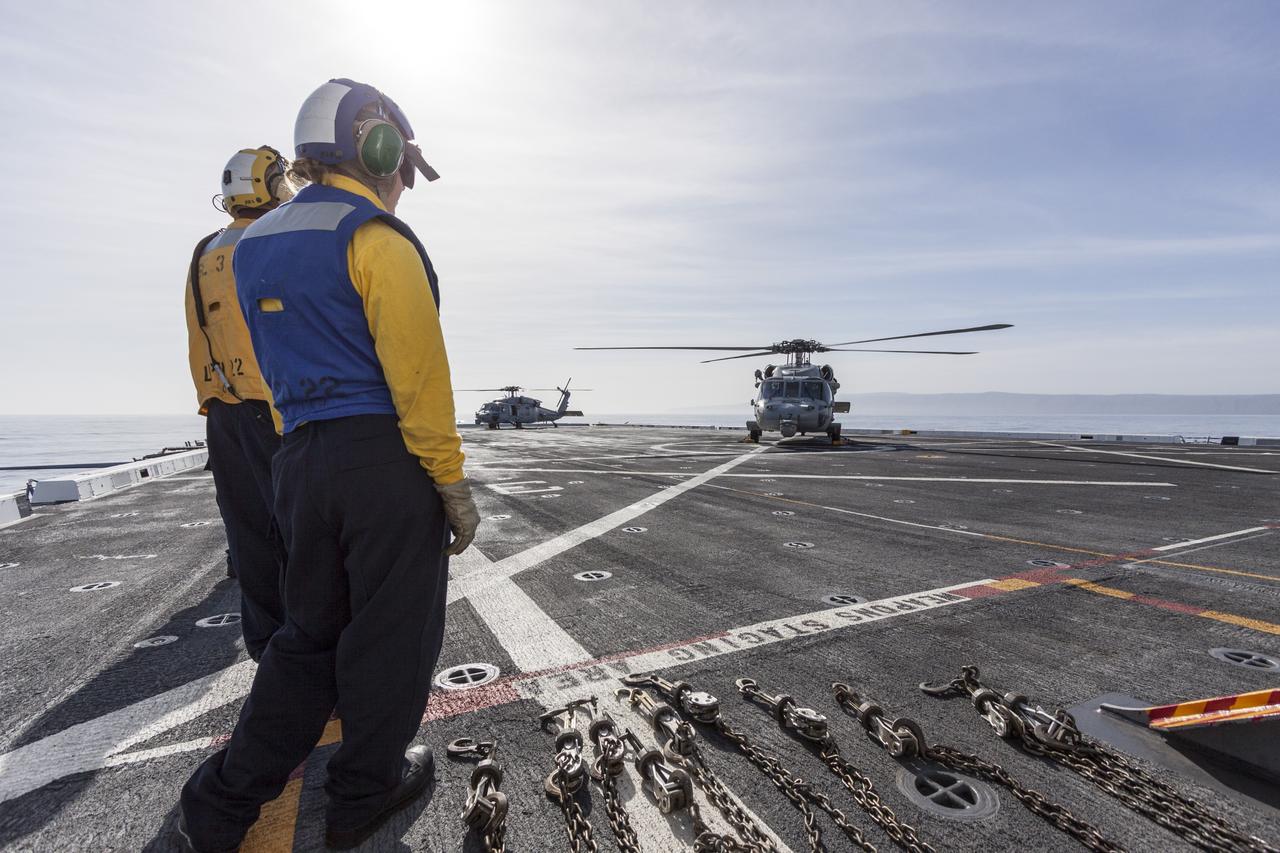 SAN DIEGO, Calif. – On the top deck of the USS San Diego, U.S. Navy personnel monitor a helicopter landing after an Orion underway recovery test. The Orion boilerplate test vehicle and other hardware were transported in the ship’s well deck about 100 miles offshore for an underway recovery test. NASA and the U.S. Navy conducted tests to prepare for recovery of the Orion crew module, forward bay cover and parachutes on its return from a deep space mission. The underway recovery test allowed the teams to demonstrate and evaluate the recovery processes, procedures, hardware and personnel in open waters. During the testing, the tether lines were unable to support the tension caused by crew module motion that was driven by wave turbulence in the well deck of the ship. NASA and the U.S. Navy are reviewing the testing data collected to evaluate the next steps. The Ground Systems Development and Operations Program conducted the underway recovery tests. Orion is the exploration spacecraft designed to carry astronauts to destinations not yet explored by humans, including an asteroid and Mars. It will have emergency abort capability, sustain the crew during space travel and provide safe re-entry from deep space return velocities. The first unpiloted test flight of the Orion is scheduled to launch in 2014 atop a Delta IV rocket and in 2017 on NASA’s Space Launch System rocket. For more information, visit http://www.nasa.gov/orion. Photo credit: NASA/Cory Huston