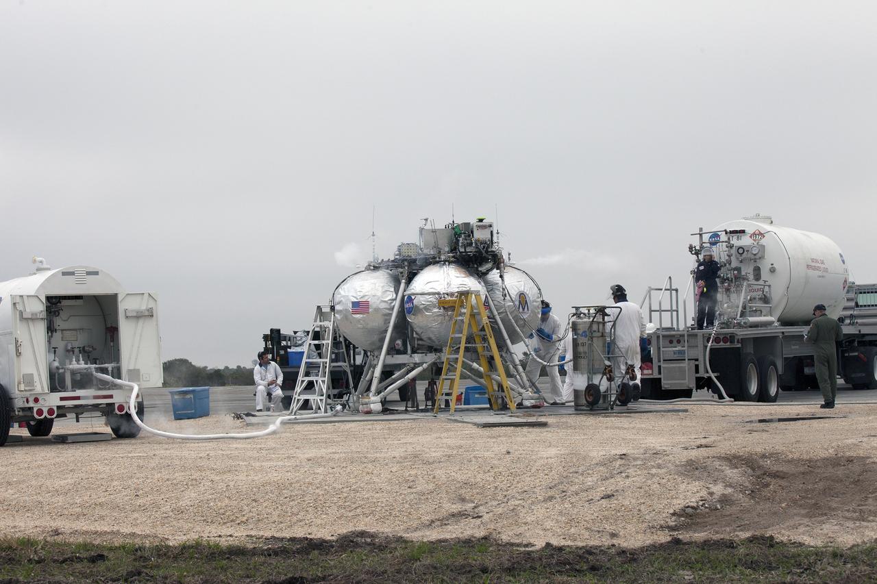 CAPE CANAVERAL, Fla. – Engineers and technicians prepare the Project Morpheus prototype lander for its sixth free flight test from a launch pad at the north end of the Shuttle Landing Facility at NASA’s Kennedy Space Center in Florida. The 82-second test began at 11:32 a.m. EST with the Morpheus lander launching from the ground over a flame trench and ascending to 465 feet. The lander flew forward, covering 633 feet while performing a 55-foot divert to emulate a hazard avoidance maneuver before descending and landing on a dedicated pad inside the automated landing and hazard avoidance technology, or ALHAT, hazard field. Morpheus landed 10 inches west of its intended target. Project Morpheus tests NASA’s ALHAT and an engine that runs on liquid oxygen and methane, or green propellants, into a fully-operational lander that could deliver cargo to other planetary surfaces. The landing facility provides the lander with the kind of field necessary for realistic testing, complete with rocks, craters and hazards to avoid. Morpheus’ ALHAT payload allows it to navigate to clear landing sites amidst rocks, craters and other hazards during its descent. Project Morpheus is being managed under the Advanced Exploration Systems, or AES, Division in NASA’s Human Exploration and Operations Mission Directorate. The efforts in AES pioneer new approaches for rapidly developing prototype systems, demonstrating key capabilities and validating operational concepts for future human missions beyond Earth orbit. For more information on Project Morpheus, visit http://morpheuslander.jsc.nasa.gov/. Photo credit: NASA/Kim Shiflett