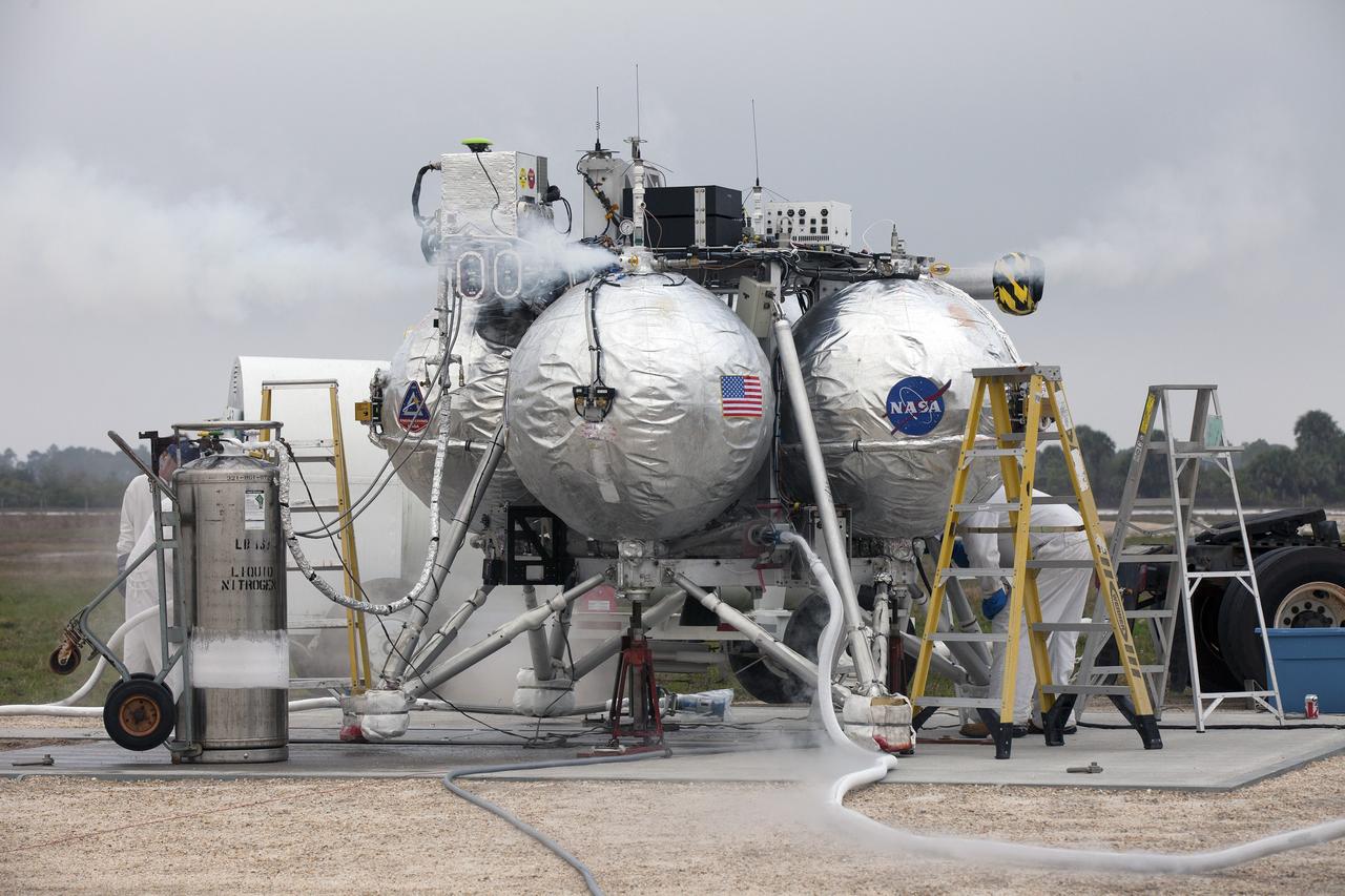 CAPE CANAVERAL, Fla. – Engineers and technicians prepare the Project Morpheus prototype lander for its sixth free flight test from a launch pad at the north end of the Shuttle Landing Facility at NASA’s Kennedy Space Center in Florida. The 82-second test began at 11:32 a.m. EST with the Morpheus lander launching from the ground over a flame trench and ascending to 465 feet. The lander flew forward, covering 633 feet while performing a 55-foot divert to emulate a hazard avoidance maneuver before descending and landing on a dedicated pad inside the automated landing and hazard avoidance technology, or ALHAT, hazard field. Morpheus landed 10 inches west of its intended target. Project Morpheus tests NASA’s ALHAT and an engine that runs on liquid oxygen and methane, or green propellants, into a fully-operational lander that could deliver cargo to other planetary surfaces. The landing facility provides the lander with the kind of field necessary for realistic testing, complete with rocks, craters and hazards to avoid. Morpheus’ ALHAT payload allows it to navigate to clear landing sites amidst rocks, craters and other hazards during its descent. Project Morpheus is being managed under the Advanced Exploration Systems, or AES, Division in NASA’s Human Exploration and Operations Mission Directorate. The efforts in AES pioneer new approaches for rapidly developing prototype systems, demonstrating key capabilities and validating operational concepts for future human missions beyond Earth orbit. For more information on Project Morpheus, visit http://morpheuslander.jsc.nasa.gov/. Photo credit: NASA/Kim Shiflett