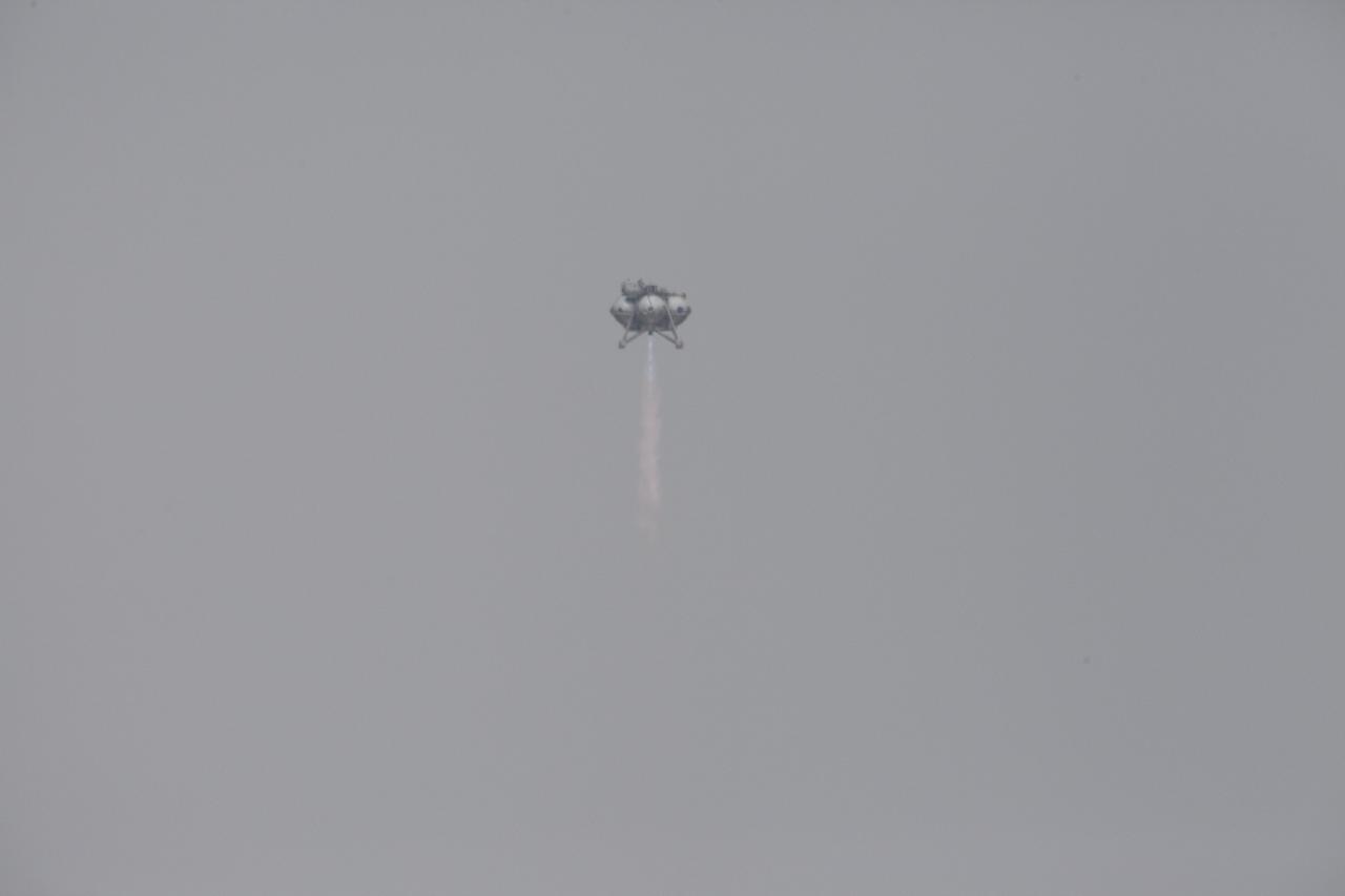 CAPE CANAVERAL, Fla. – The Project Morpheus prototype lander soars high after launching on its sixth free flight test at the north end of the Shuttle Landing Facility at NASA’s Kennedy Space Center in Florida. The 82-second test began at 11:32 a.m. EST with the Morpheus lander launching from the ground over a flame trench and ascending to 465 feet. The lander flew forward, covering 633 feet while performing a 55-foot divert to emulate a hazard avoidance maneuver before descending and landing on a dedicated pad inside the automated landing and hazard avoidance technology, or ALHAT, hazard field. Morpheus landed 10 inches west of its intended target. Project Morpheus tests NASA’s ALHAT and an engine that runs on liquid oxygen and methane, or green propellants, into a fully-operational lander that could deliver cargo to other planetary surfaces. The landing facility provides the lander with the kind of field necessary for realistic testing, complete with rocks, craters and hazards to avoid. Morpheus’ ALHAT payload allows it to navigate to clear landing sites amidst rocks, craters and other hazards during its descent. Project Morpheus is being managed under the Advanced Exploration Systems, or AES, Division in NASA’s Human Exploration and Operations Mission Directorate. The efforts in AES pioneer new approaches for rapidly developing prototype systems, demonstrating key capabilities and validating operational concepts for future human missions beyond Earth orbit. For more information on Project Morpheus, visit http://morpheuslander.jsc.nasa.gov/. Photo credit: NASA/Kim Shiflett