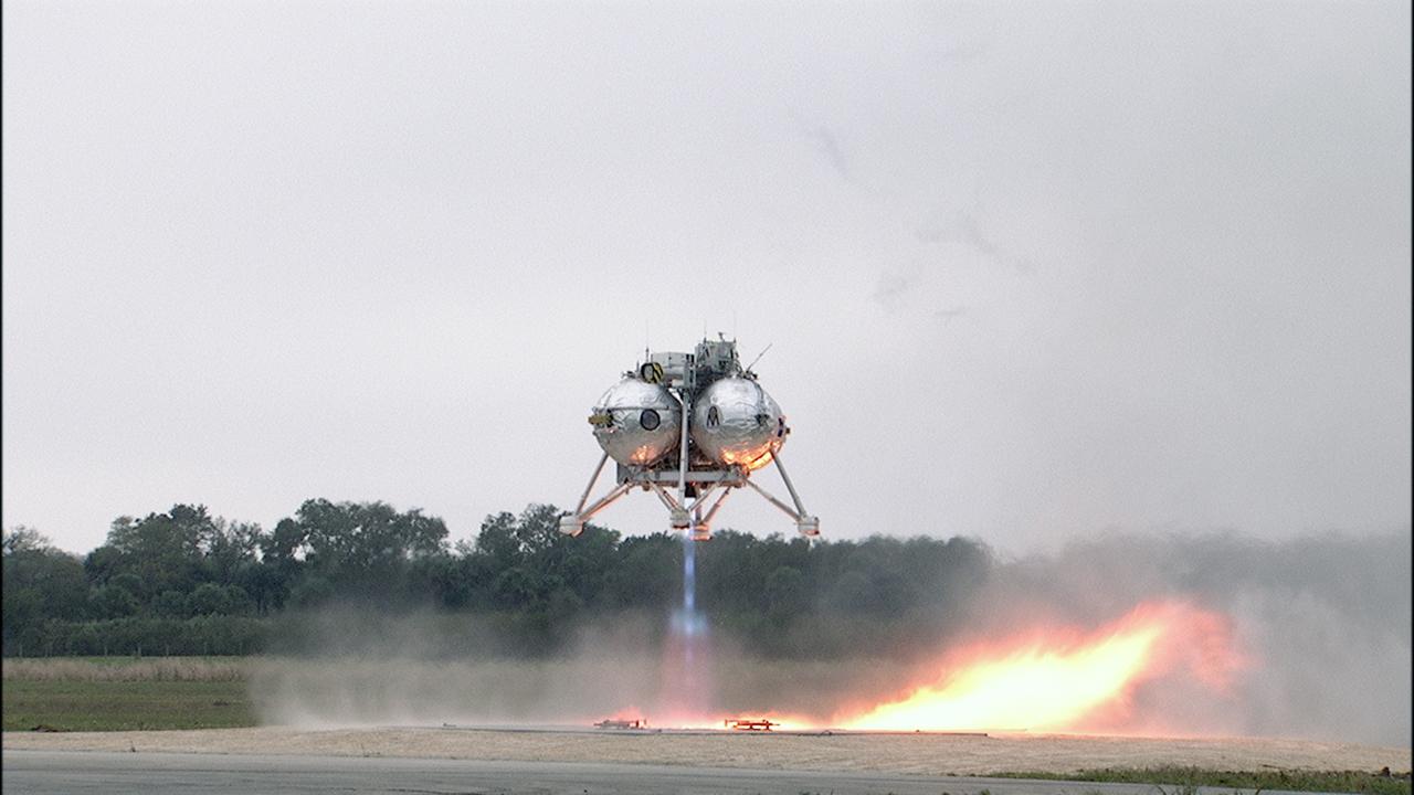 CAPE CANAVERAL, Fla. – The Project Morpheus prototype lander begins to ascend on its sixth free flight test at the north end of the Shuttle Landing Facility at NASA’s Kennedy Space Center in Florida. The 82-second test began at 11:32 a.m. EST with the Morpheus lander launching from the ground over a flame trench and ascending to 465 feet. The lander flew forward, covering 633 feet while performing a 55-foot divert to emulate a hazard avoidance maneuver before descending and landing on a dedicated pad inside the automated landing and hazard avoidance technology, or ALHAT, hazard field. Morpheus landed 10 inches west of its intended target. Project Morpheus tests NASA’s ALHAT and an engine that runs on liquid oxygen and methane, or green propellants, into a fully-operational lander that could deliver cargo to other planetary surfaces. The landing facility provides the lander with the kind of field necessary for realistic testing, complete with rocks, craters and hazards to avoid. Morpheus’ ALHAT payload allows it to navigate to clear landing sites amidst rocks, craters and other hazards during its descent. Project Morpheus is being managed under the Advanced Exploration Systems, or AES, Division in NASA’s Human Exploration and Operations Mission Directorate. The efforts in AES pioneer new approaches for rapidly developing prototype systems, demonstrating key capabilities and validating operational concepts for future human missions beyond Earth orbit. For more information on Project Morpheus, visit http://morpheuslander.jsc.nasa.gov/. Photo credit: NASA/Frankie Martin