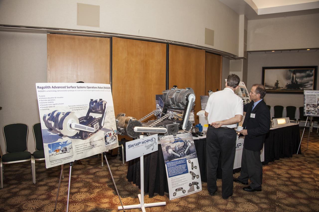 CAPE CANAVERAL, Fla. - Community leaders, business executives, educators, and state and local government leaders were updated on NASA Kennedy Space Center programs and accomplishments during Center Director Bob Cabana’s Center Director Update at the Debus Center at the Kennedy Space Center Visitor Complex in Florida. Rob Mueller, a senior technologist, talks to an attendee about Kennedy’s Swamp Works Laboratory. Attendees talked with Cabana and other senior Kennedy managers and visited displays featuring updates on Kennedy programs and projects, including International Space Station, Commercial Crew, Ground System Development and Operations, Launch Services, Center Planning and Development, Technology, KSC Swamp Works and NASA Education. The morning concluded with a tour of the new Space Shuttle Atlantis exhibit at the visitor complex. For more information, visit http://www.nasa.gov/kennedy. Photo credit: NASA/Daniel Casper