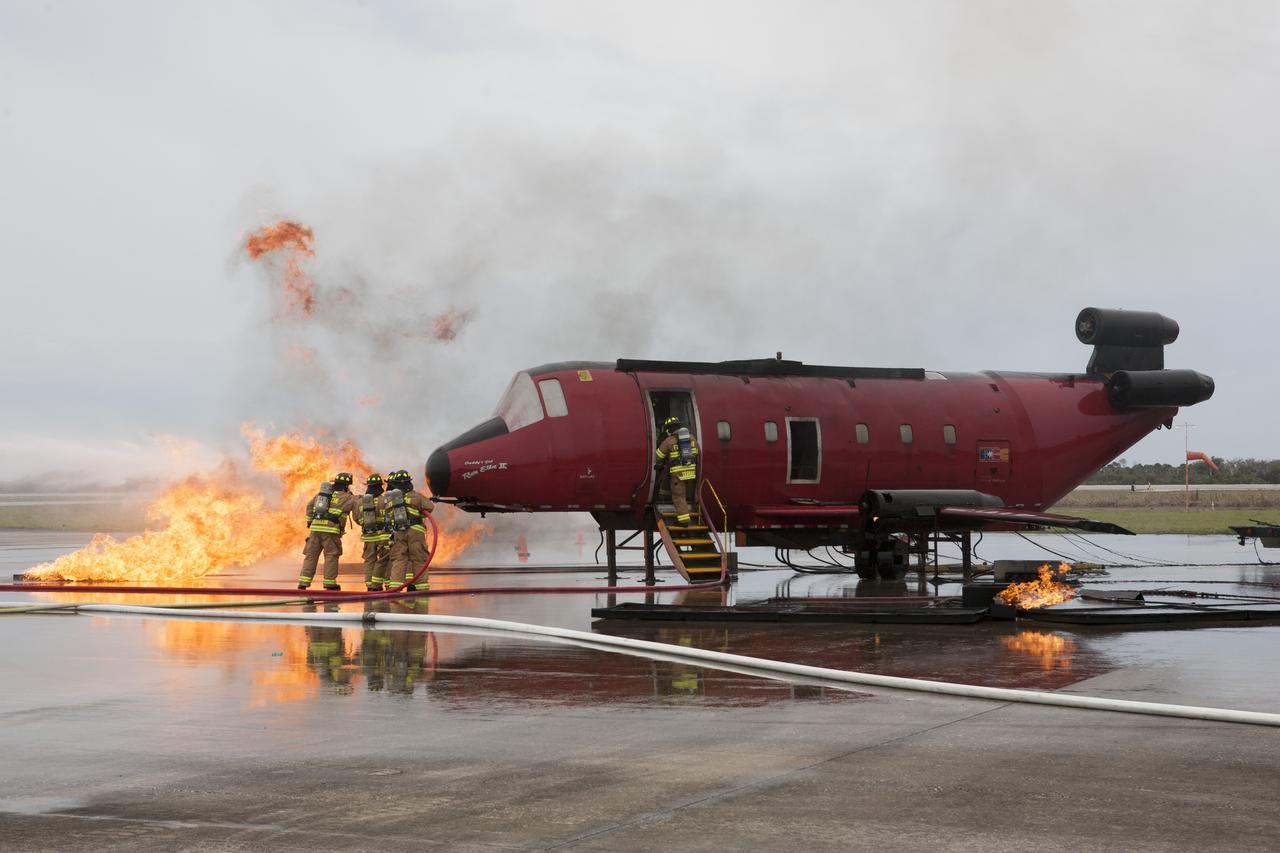 CAPE CANAVERAL, Fla. - Special Rescue Operations firefighters with NASA Fire Rescue Services in the Protective Services Office at NASA’s Kennedy Space Center in Florida participate in a training exercise at the Shuttle Landing Facility. Firefighters, wearing protective gear, use hoses to put out a fire burning near the mock-up of a small plane as another firefighter checks inside the plane. Kennedy’s firefighters recently achieved Pro Board Certification in aerial fire truck operations and completed vehicle extrication training using the Jaws of Life. The Protective Services Office is one step closer to achieving certification in vehicle machinery extrication and other rescue skills. Kennedy’s firefighters are with G4S Government Solutions Inc., on the Kennedy Protective Services Contract. Photo credit: NASA/Kim Shiflett