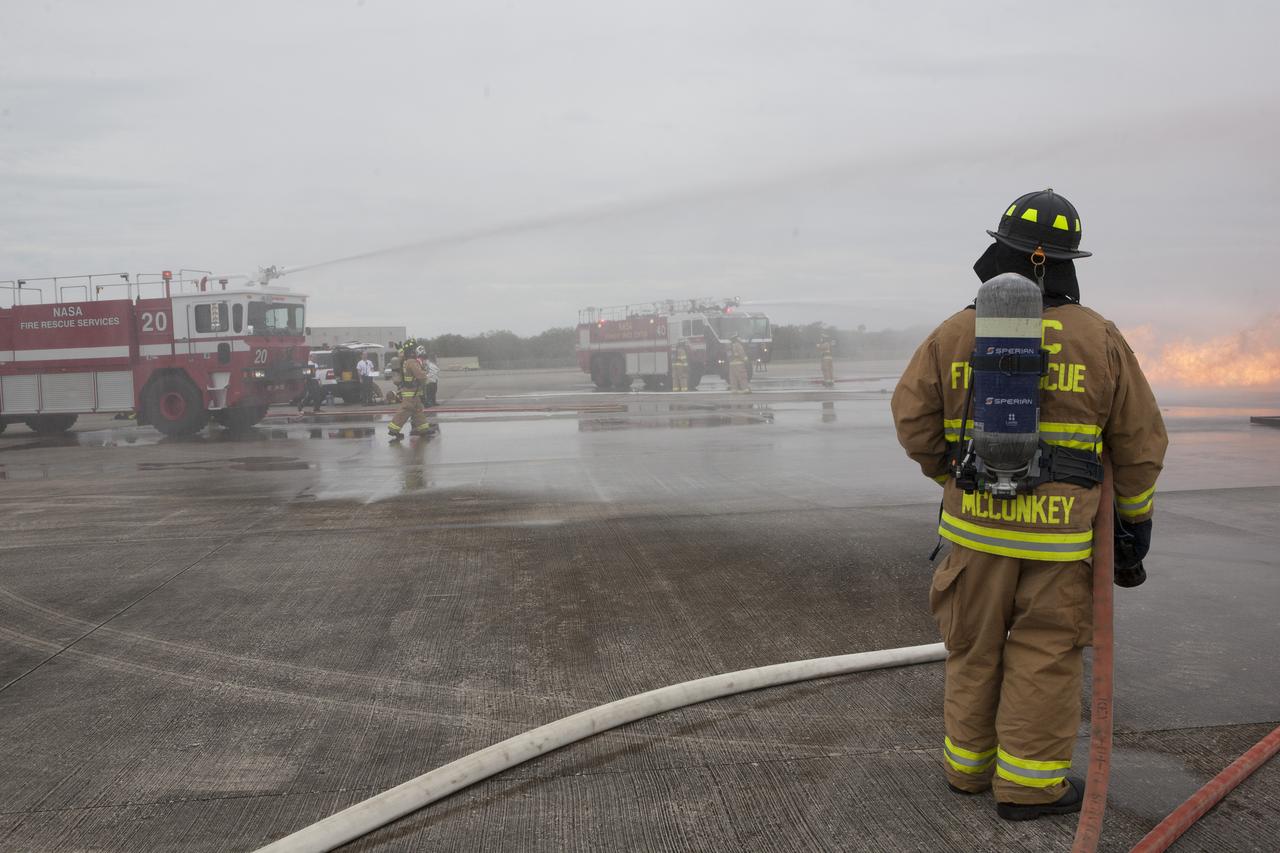 CAPE CANAVERAL, Fla. - Special Rescue Operations firefighters with NASA Fire Rescue Services in the Protective Services Office at NASA’s Kennedy Space Center in Florida prepare to participate in a training exercise at the Shuttle Landing Facility. A small fire is burning near a mock-up of a plane during the training exercise. Kennedy’s firefighters recently achieved Pro Board Certification in aerial fire truck operations and completed vehicle extrication training using the Jaws of Life. The Protective Services Office is one step closer to achieving certification in vehicle machinery extrication and other rescue skills. Kennedy’s firefighters are with G4S Government Solutions Inc., on the Kennedy Protective Services Contract. Photo credit: NASA/Kim Shiflett