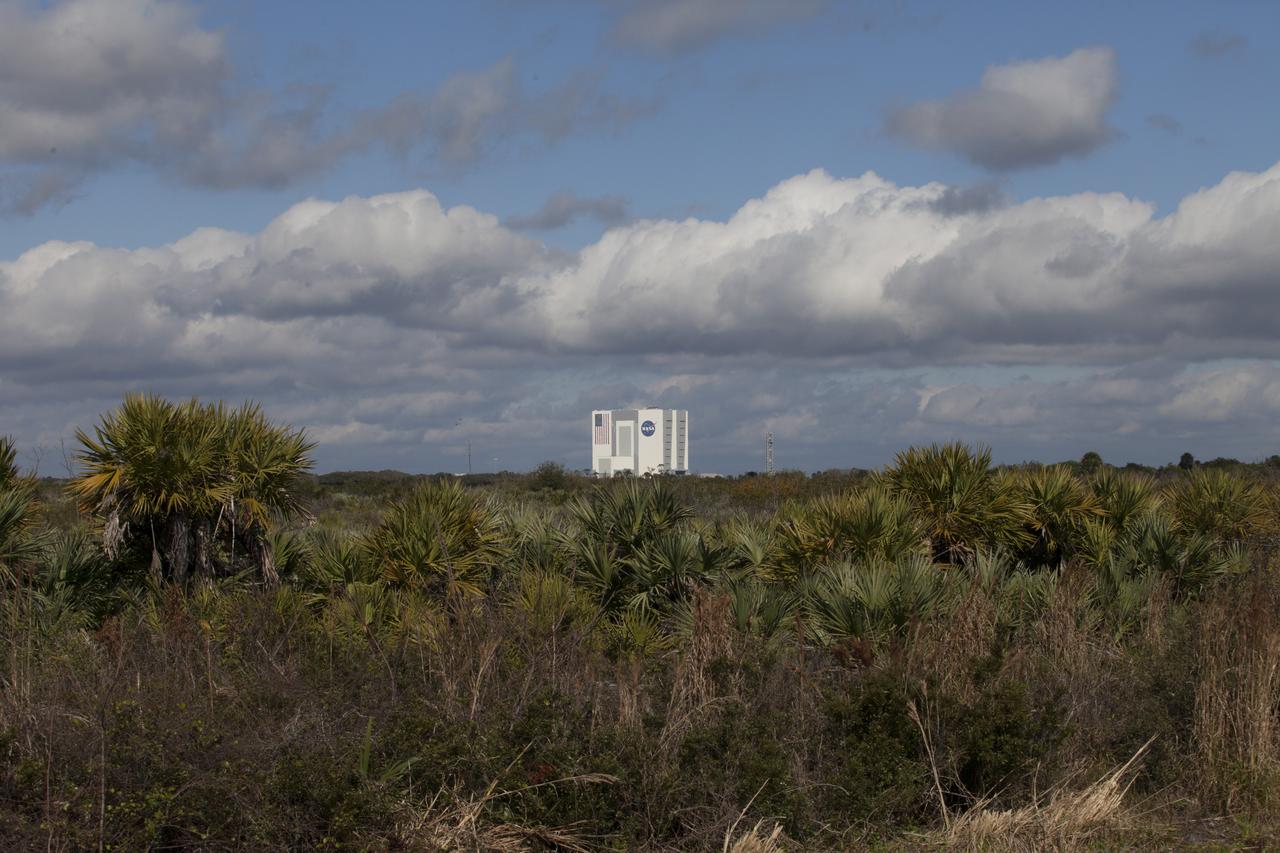 CAPE CANAVERAL, Fla. - With palm trees and underbrush in the foreground, the Vehicle Assembly Building is visible in this view looking west at NASA’s Kennedy Space Center in Florida. The center shares a boundary with the Merritt Island National Wildlife Refuge. The refuge encompasses 140,000 acres that are a habitat for more than 330 species of birds, 31 mammals, 117 fishes, and 65 amphibians and reptiles. It contains more than 1,000 known plant species. The marshes and open water of the refuge provide wintering areas for 23 species of migratory waterfowl, as well as a year-round home for great blue herons, great egrets, wood storks, cormorants, brown pelicans and other species of marsh and shore birds, and a variety of insects. Photo credit: NASA/Daniel Casper