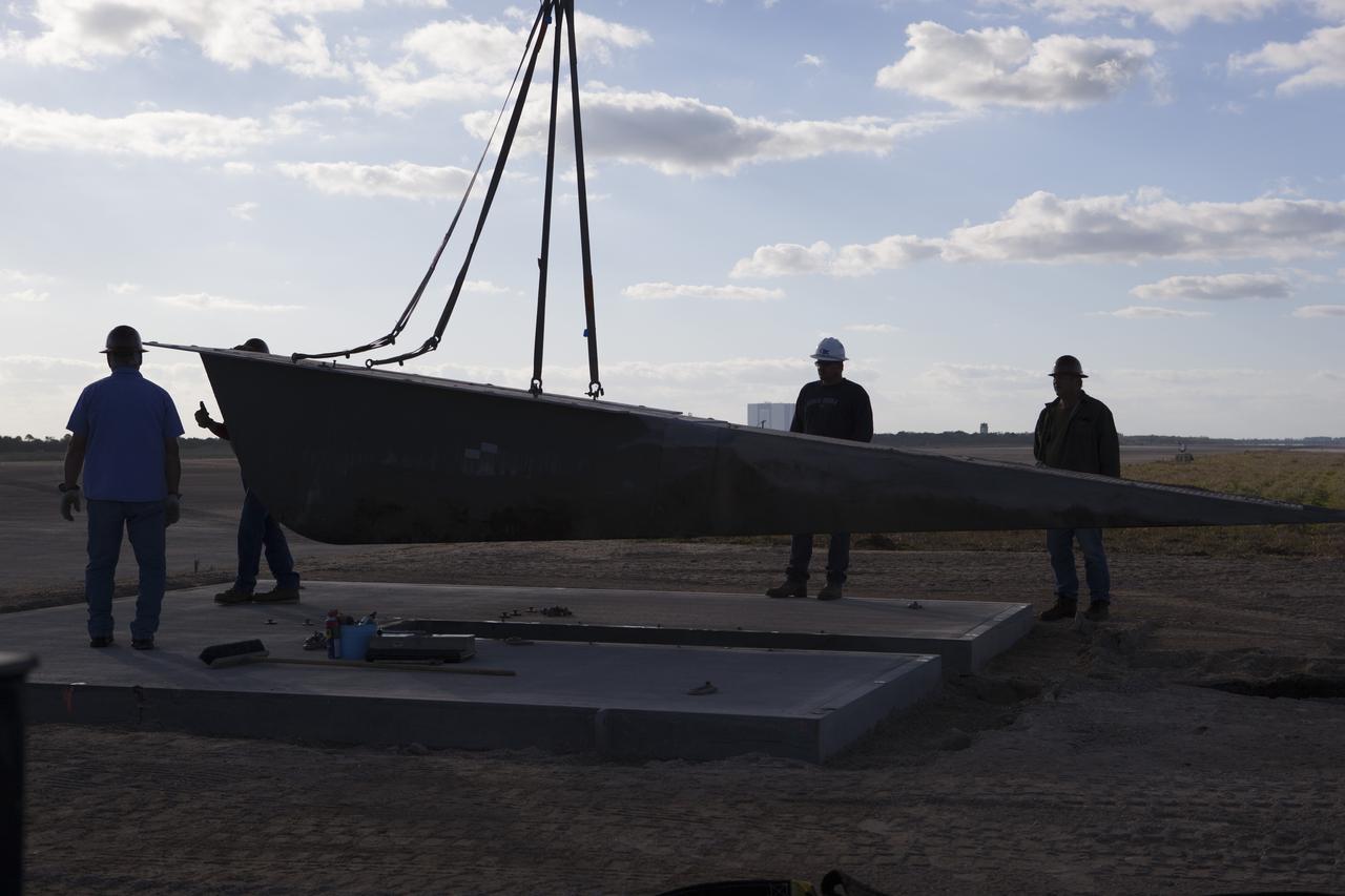 CAPE CANAVERAL, Fla. – Construction workers monitor the progress as a crane is used to lift a portion of the launch pad for the Project Morpheus prototype lander at the north end of the Shuttle Landing Facility at NASA’s Kennedy Space Center in Florida. The launch pad will be moved to a different location at the landing facility to support the next phase of flight testing. The seventh free flight test of Morpheus occurred on March 11. The 83-second test began at 3:41 p.m. EDT with the Morpheus lander launching from the ground over a flame trench and ascending to 580 feet. Morpheus then flew its fastest downrange trek at 30 mph, travelling farther than before, 837 feet. The lander performed a 42-foot divert to emulate a hazard avoidance maneuver before descending and touching down on Landing Site 2, at the northern landing pad inside the automated landing and hazard avoidance technology ALHAT hazard field. Morpheus landed within one foot of its intended target. Project Morpheus tests NASA’s ALHAT and an engine that runs on liquid oxygen and methane, or green propellants, into a fully-operational lander that could deliver cargo to other planetary surfaces . The landing facility provides the lander with the kind of field necessary for realistic testing, complete with rocks, craters and hazards to avoid. Morpheus’ ALHAT payload allows it to navigate to clear landing sites amidst rocks, craters and other hazards during its descent. Project Morpheus is being managed under the Advanced Exploration Systems, or AES, Division in NASA’s Human Exploration and Operations Mission Directorate. The efforts in AES pioneer new approaches for rapidly developing prototype systems, demonstrating key capabilities and validating operational concepts for future human missions beyond Earth orbit. For more information on Project Morpheus, visit http://morpheuslander.jsc.nasa.gov/. Photo credit: NASA/Dimitri Gerondidakis