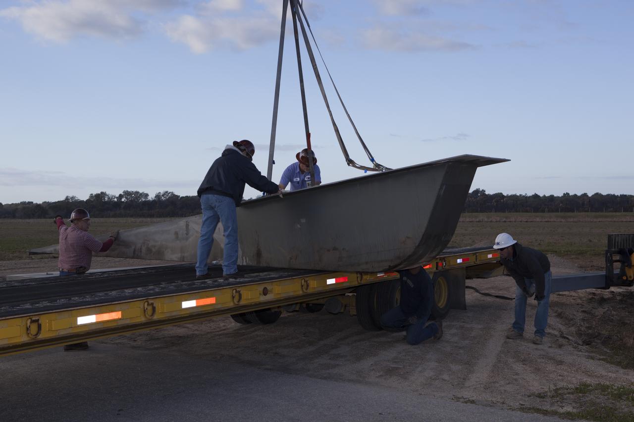 CAPE CANAVERAL, Fla. – Construction workers assist as a crane lowers a portion of the launch pad for the Project Morpheus prototype lander onto a transporter at the north end of the Shuttle Landing Facility at NASA’s Kennedy Space Center in Florida. The launch pad is being moved to a different location at the landing facility to support the next phase of flight testing. Morpheus completed its seventh free flight test on March 11. The 83-second test began at 3:41 p.m. EDT with the Morpheus lander launching from the ground over a flame trench and ascending to 580 feet. Morpheus then flew its fastest downrange trek at 30 mph, travelling farther than before, 837 feet. The lander performed a 42-foot divert to emulate a hazard avoidance maneuver before descending and touching down on Landing Site 2, at the northern landing pad inside the automated landing and hazard avoidance technology ALHAT hazard field. Morpheus landed within one foot of its intended target. Project Morpheus tests NASA’s ALHAT and an engine that runs on liquid oxygen and methane, or green propellants, into a fully-operational lander that could deliver cargo to other planetary surfaces. The landing facility provides the lander with the kind of field necessary for realistic testing, complete with rocks, craters and hazards to avoid. Morpheus’ ALHAT payload allows it to navigate to clear landing sites amidst rocks, craters and other hazards during its descent. Project Morpheus is being managed under the Advanced Exploration Systems, or AES, Division in NASA’s Human Exploration and Operations Mission Directorate. The efforts in AES pioneer new approaches for rapidly developing prototype systems, demonstrating key capabilities and validating operational concepts for future human missions beyond Earth orbit. For more information on Project Morpheus, visit http://morpheuslander.jsc.nasa.gov/. Photo credit: NASA/Dimitri Gerondidakis