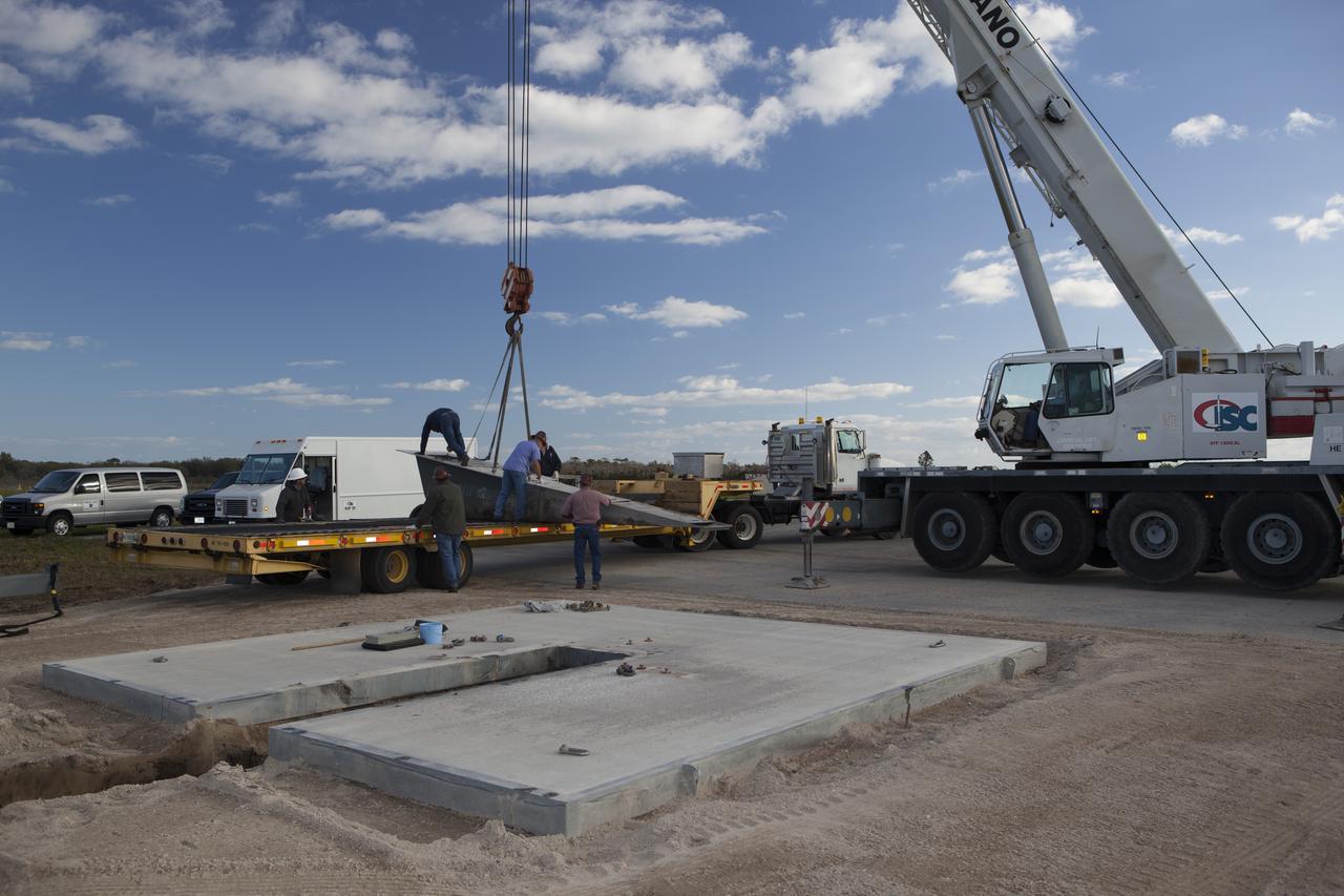 CAPE CANAVERAL, Fla. – Construction workers assist as a crane lowers a portion of the launch pad for the Project Morpheus prototype lander onto a transporter at the north end of the Shuttle Landing Facility at NASA’s Kennedy Space Center in Florida. The launch pad is being moved to a different location at the landing facility to support the next phase of flight testing. Morpheus completed its seventh free flight test on March 11. The 83-second test began at 3:41 p.m. EDT with the Morpheus lander launching from the ground over a flame trench and ascending to 580 feet. Morpheus then flew its fastest downrange trek at 30 mph, travelling farther than before, 837 feet. The lander performed a 42-foot divert to emulate a hazard avoidance maneuver before descending and touching down on Landing Site 2, at the northern landing pad inside the automated landing and hazard avoidance technology ALHAT hazard field. Morpheus landed within one foot of its intended target. Project Morpheus tests NASA’s ALHAT and an engine that runs on liquid oxygen and methane, or green propellants, into a fully-operational lander that could deliver cargo to other planetary surfaces. The landing facility provides the lander with the kind of field necessary for realistic testing, complete with rocks, craters and hazards to avoid. Morpheus’ ALHAT payload allows it to navigate to clear landing sites amidst rocks, craters and other hazards during its descent. Project Morpheus is being managed under the Advanced Exploration Systems, or AES, Division in NASA’s Human Exploration and Operations Mission Directorate. The efforts in AES pioneer new approaches for rapidly developing prototype systems, demonstrating key capabilities and validating operational concepts for future human missions beyond Earth orbit. For more information on Project Morpheus, visit http://morpheuslander.jsc.nasa.gov/. Photo credit: NASA/Dimitri Gerondidakis