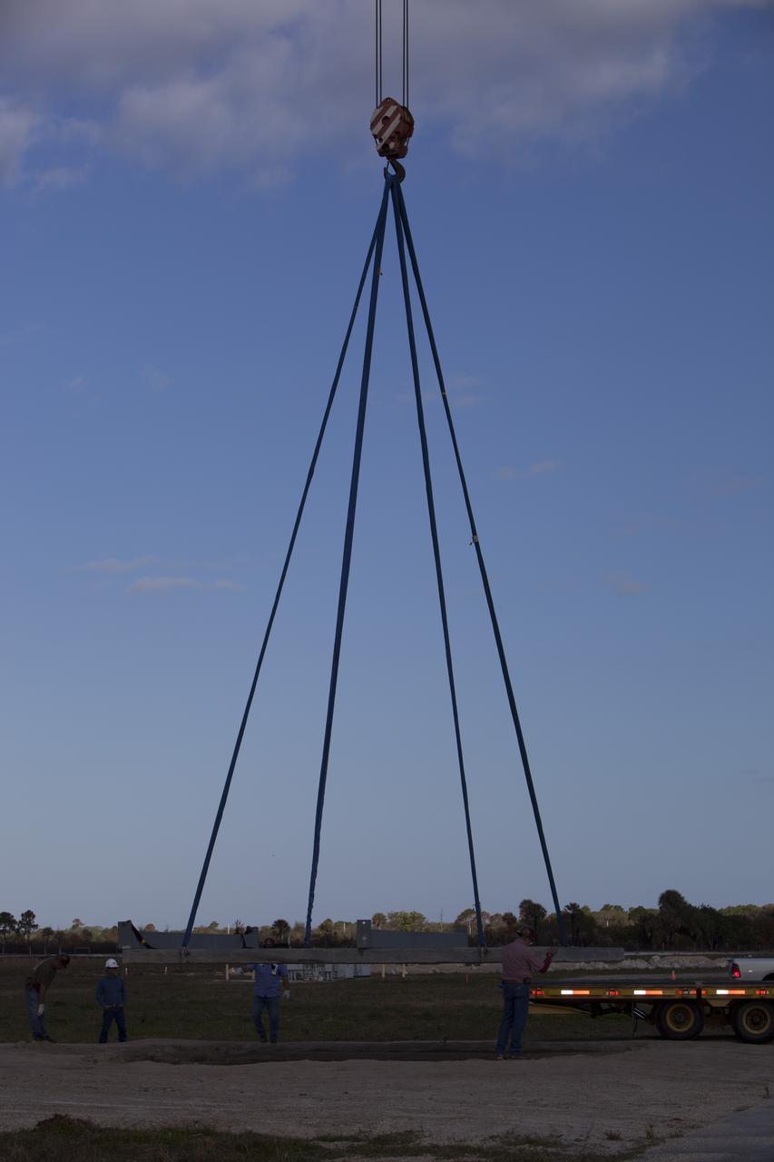 CAPE CANAVERAL, Fla. – Construction workers assist as a crane is used to lift a large portion of the launch pad for the Project Morpheus prototype lander onto a transporter at the north end of the Shuttle Landing Facility at NASA’s Kennedy Space Center in Florida. The launch pad is being moved to a different location at the landing facility to support the next phase of flight testing. Morpheus completed its seventh free flight test on March 11. The 83-second test began at 3:41 p.m. EDT with the Morpheus lander launching from the ground over a flame trench and ascending to 580 feet. Morpheus then flew its fastest downrange trek at 30 mph, travelling farther than before, 837 feet. The lander performed a 42-foot divert to emulate a hazard avoidance maneuver before descending and touching down on Landing Site 2, at the northern landing pad inside the automated landing and hazard avoidance technology ALHAT hazard field. Morpheus landed within one foot of its intended target. Project Morpheus tests NASA’s ALHAT and an engine that runs on liquid oxygen and methane, or green propellants, into a fully-operational lander that could deliver cargo to other planetary surfaces. The landing facility provides the lander with the kind of field necessary for realistic testing, complete with rocks, craters and hazards to avoid. Morpheus’ ALHAT payload allows it to navigate to clear landing sites amidst rocks, craters and other hazards during its descent. Project Morpheus is being managed under the Advanced Exploration Systems, or AES, Division in NASA’s Human Exploration and Operations Mission Directorate. The efforts in AES pioneer new approaches for rapidly developing prototype systems, demonstrating key capabilities and validating operational concepts for future human missions beyond Earth orbit. For more information on Project Morpheus, visit http://morpheuslander.jsc.nasa.gov/. Photo credit: NASA/Dimitri Gerondidakis