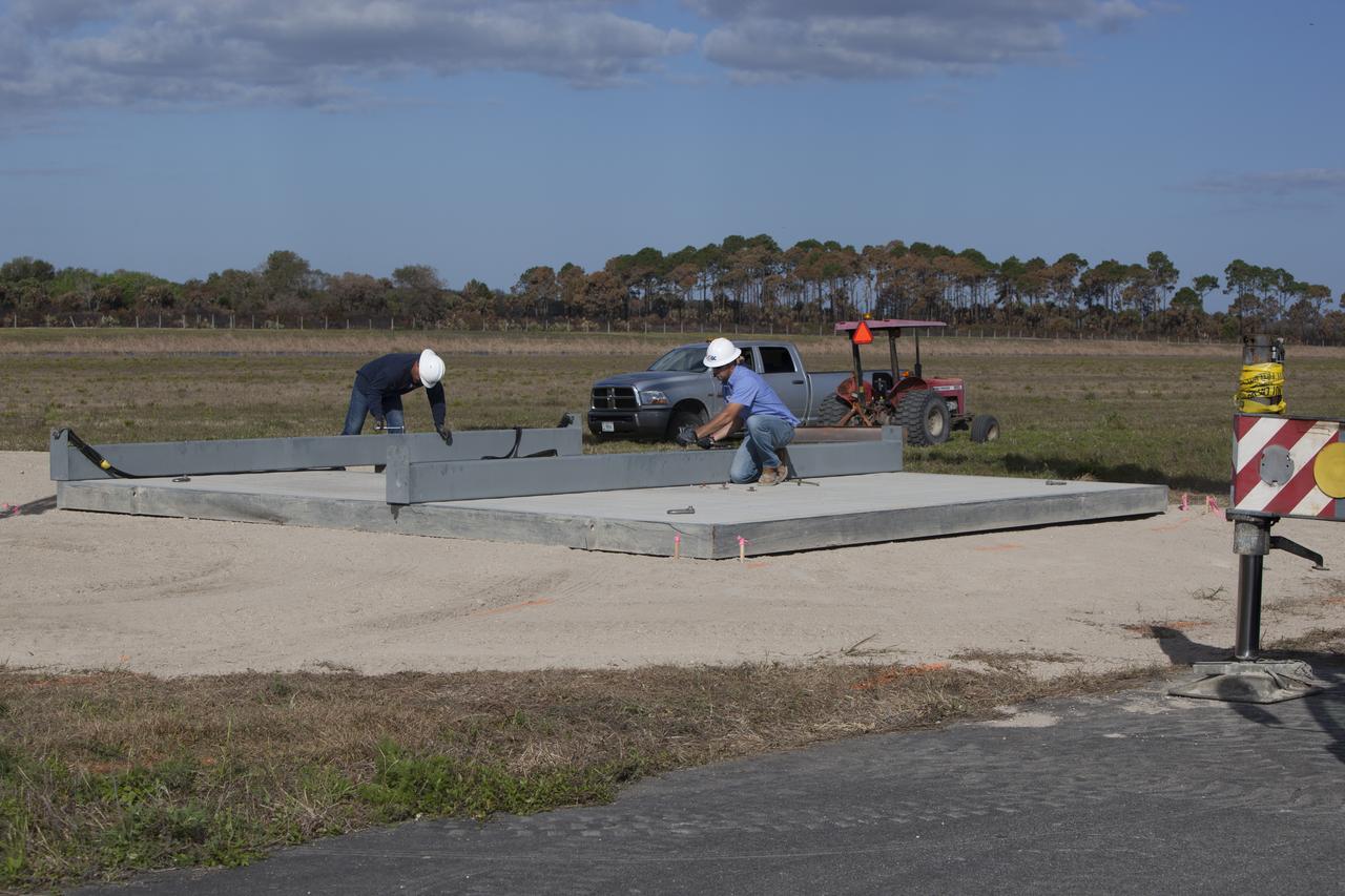 CAPE CANAVERAL, Fla. – Construction workers begin to reassemble the launch pad for the Project Morpheus prototype lander at a new location at the north end of the Shuttle Landing Facility at NASA’s Kennedy Space Center in Florida. The launch pad was moved to a different location to support the next phase of flight testing. Morpheus completed its seventh free flight test on March 11. The 83-second test began at 3:41 p.m. EDT with the Morpheus lander launching from the ground over a flame trench and ascending to 580 feet. Morpheus then flew its fastest downrange trek at 30 mph, travelling farther than before, 837 feet. The lander performed a 42-foot divert to emulate a hazard avoidance maneuver before descending and touching down on Landing Site 2, at the northern landing pad inside the automated landing and hazard avoidance technology ALHAT hazard field. Morpheus landed within one foot of its intended target. Project Morpheus tests NASA’s ALHAT and an engine that runs on liquid oxygen and methane, or green propellants, into a fully-operational lander that could deliver cargo to other planetary surfaces. The landing facility provides the lander with the kind of field necessary for realistic testing, complete with rocks, craters and hazards to avoid. Morpheus’ ALHAT payload allows it to navigate to clear landing sites amidst rocks, craters and other hazards during its descent. Project Morpheus is being managed under the Advanced Exploration Systems, or AES, Division in NASA’s Human Exploration and Operations Mission Directorate. The efforts in AES pioneer new approaches for rapidly developing prototype systems, demonstrating key capabilities and validating operational concepts for future human missions beyond Earth orbit. For more information on Project Morpheus, visit http://morpheuslander.jsc.nasa.gov/. Photo credit: NASA/Dimitri Gerondidakis