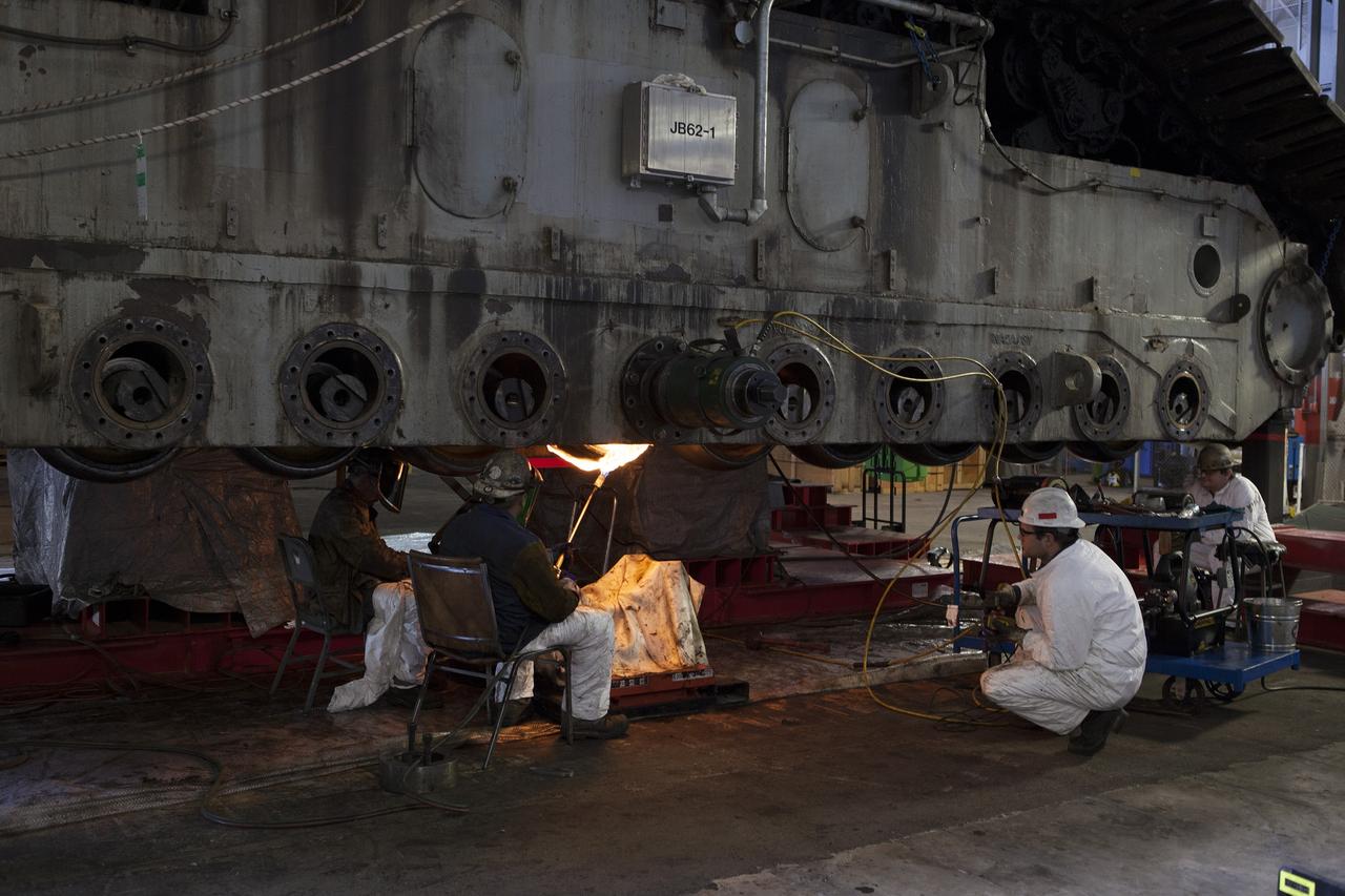 CAPE CANAVERAL, Fla. – Inside the Vehicle Assembly Building at NASA’s Kennedy Space Center in Florida, a ground support technician applies heat to a casing that contains an old bearing on the B truck tread of crawler-transporter 2, or CT-2, as other technicians monitor the progress. The bearing will separate and out for removal. New roller bearing assemblies will be installed on CT-2. Work continues in high bay 2 to upgrade CT-2. The modifications are designed to ensure CT-2’s ability to transport launch vehicles currently in development, such as the agency’s Space Launch System, to the launch pad. The Ground Systems Development and Operations Program office at Kennedy is overseeing the upgrades. For more than 45 years the crawler-transporters were used to transport the mobile launcher platform and the Apollo-Saturn V rockets and, later, space shuttles to Launch Pads 39A and B. For more information, visit: http://www.nasa.gov/exploration/systems/ground/crawler-transporter. Photo credit: NASA/Dimitri Gerondidakis