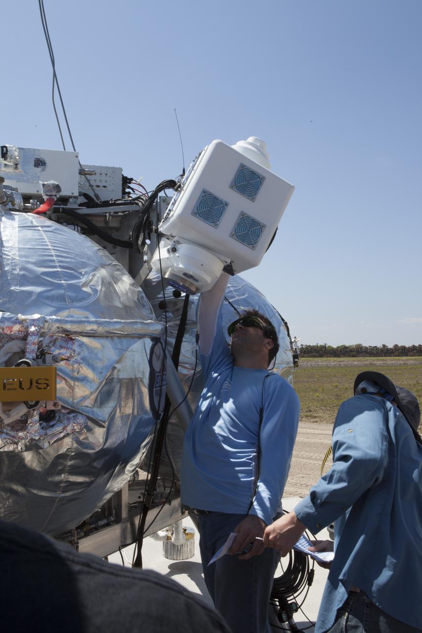 CAPE CANAVERAL, Fla. – Engineers and technicians wearing safety goggles, prepare the Project Morpheus prototype lander for an automated landing and hazard avoidance technology, or ALHAT, and laser test at a new launch site at the north end of the Shuttle Landing Facility at NASA’s Kennedy Space Center in Florida. The launch pad was moved to a different location at the landing facility to support the next phase of flight testing. The seventh free flight test of Morpheus occurred on March 11. The 83-second test began at 3:41 p.m. EDT with the Morpheus lander launching from the ground over a flame trench and ascending to 580 feet. Morpheus then flew its fastest downrange trek at 30 mph, travelling farther than before, 837 feet. The lander performed a 42-foot divert to emulate a hazard avoidance maneuver before descending and touching down on Landing Site 2, at the northern landing pad inside the ALHAT hazard field. Morpheus landed within one foot of its intended target. Project Morpheus tests NASA’s ALHAT and an engine that runs on liquid oxygen and methane, or green propellants, into a fully-operational lander that could deliver cargo to other planetary surfaces. The landing facility provides the lander with the kind of field necessary for realistic testing, complete with rocks, craters and hazards to avoid. Morpheus’ ALHAT payload allows it to navigate to clear landing sites amidst rocks, craters and other hazards during its descent. Project Morpheus is being managed under the Advanced Exploration Systems, or AES, Division in NASA’s Human Exploration and Operations Mission Directorate. The efforts in AES pioneer new approaches for rapidly developing prototype systems, demonstrating key capabilities and validating operational concepts for future human missions beyond Earth orbit. For more information on Project Morpheus, visit http://morpheuslander.jsc.nasa.gov/. Photo credit: NASA/Kim Shiflett