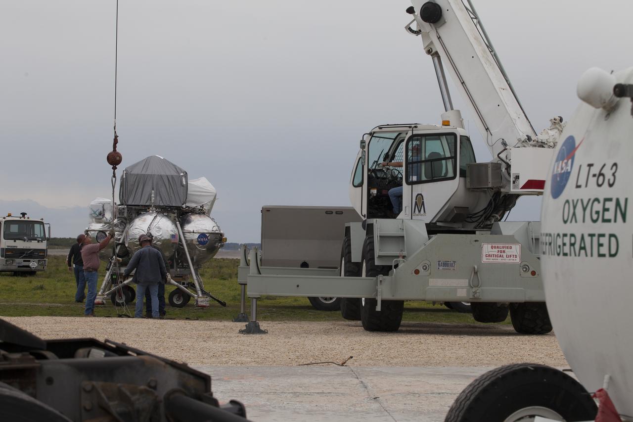 CAPE CANAVERAL, Fla. – Engineers and technicians prepare the Project Morpheus prototype lander for a tether test near a new launch site at the north end of the Shuttle Landing Facility at NASA's Kennedy Space Center in Florida. The launch pad was moved to a different location at the landing facility to support the next phase of flight testing. Project Morpheus tests NASA’s automated landing and hazard avoidance technology, or ALHAT, and an engine that runs on liquid oxygen and methane, or green propellants, into a fully-operational lander that could deliver cargo to other planetary surfaces. The landing facility provides the lander with the kind of field necessary for realistic testing, complete with rocks, craters and hazards to avoid. Morpheus’ ALHAT payload allows it to navigate to clear landing sites amidst rocks, craters and other hazards during its descent. Project Morpheus is being managed under the Advanced Exploration Systems, or AES, Division in NASA’s Human Exploration and Operations Mission Directorate. The efforts in AES pioneer new approaches for rapidly developing prototype systems, demonstrating key capabilities and validating operational concepts for future human missions beyond Earth orbit. For more information on Project Morpheus, visit http://morpheuslander.jsc.nasa.gov/. Photo credit: NASA/Ben Smegelsky