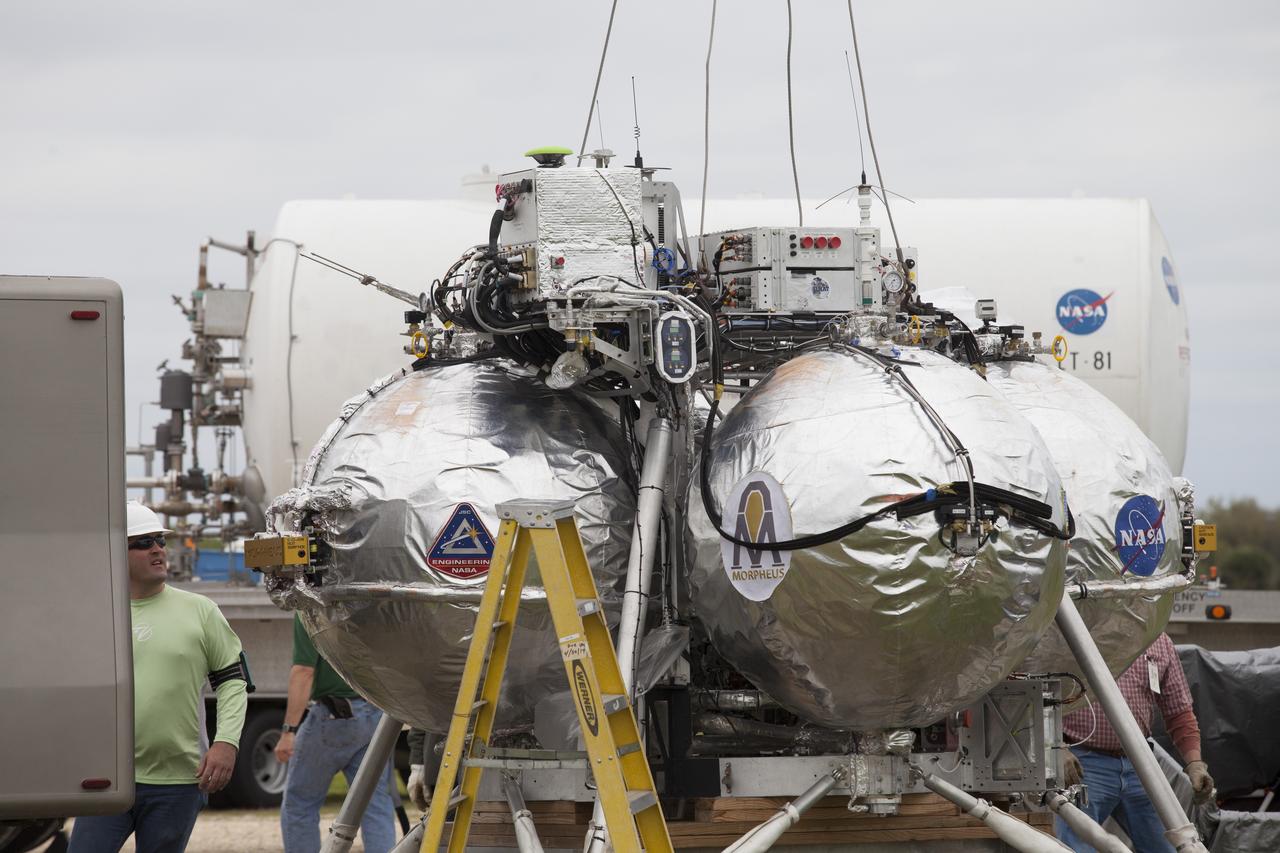 CAPE CANAVERAL, Fla. – Engineers and technicians prepare the Project Morpheus prototype lander for a tether test near a new launch site at the north end of the Shuttle Landing Facility at NASA's Kennedy Space Center in Florida. The launch pad was moved to a different location at the landing facility to support the next phase of flight testing. Project Morpheus tests NASA’s automated landing and hazard avoidance technology, or ALHAT, and an engine that runs on liquid oxygen and methane, or green propellants, into a fully-operational lander that could deliver cargo to other planetary surfaces. The landing facility provides the lander with the kind of field necessary for realistic testing, complete with rocks, craters and hazards to avoid. Morpheus’ ALHAT payload allows it to navigate to clear landing sites amidst rocks, craters and other hazards during its descent. Project Morpheus is being managed under the Advanced Exploration Systems, or AES, Division in NASA’s Human Exploration and Operations Mission Directorate. The efforts in AES pioneer new approaches for rapidly developing prototype systems, demonstrating key capabilities and validating operational concepts for future human missions beyond Earth orbit. For more information on Project Morpheus, visit http://morpheuslander.jsc.nasa.gov/. Photo credit: NASA/Ben Smegelsky