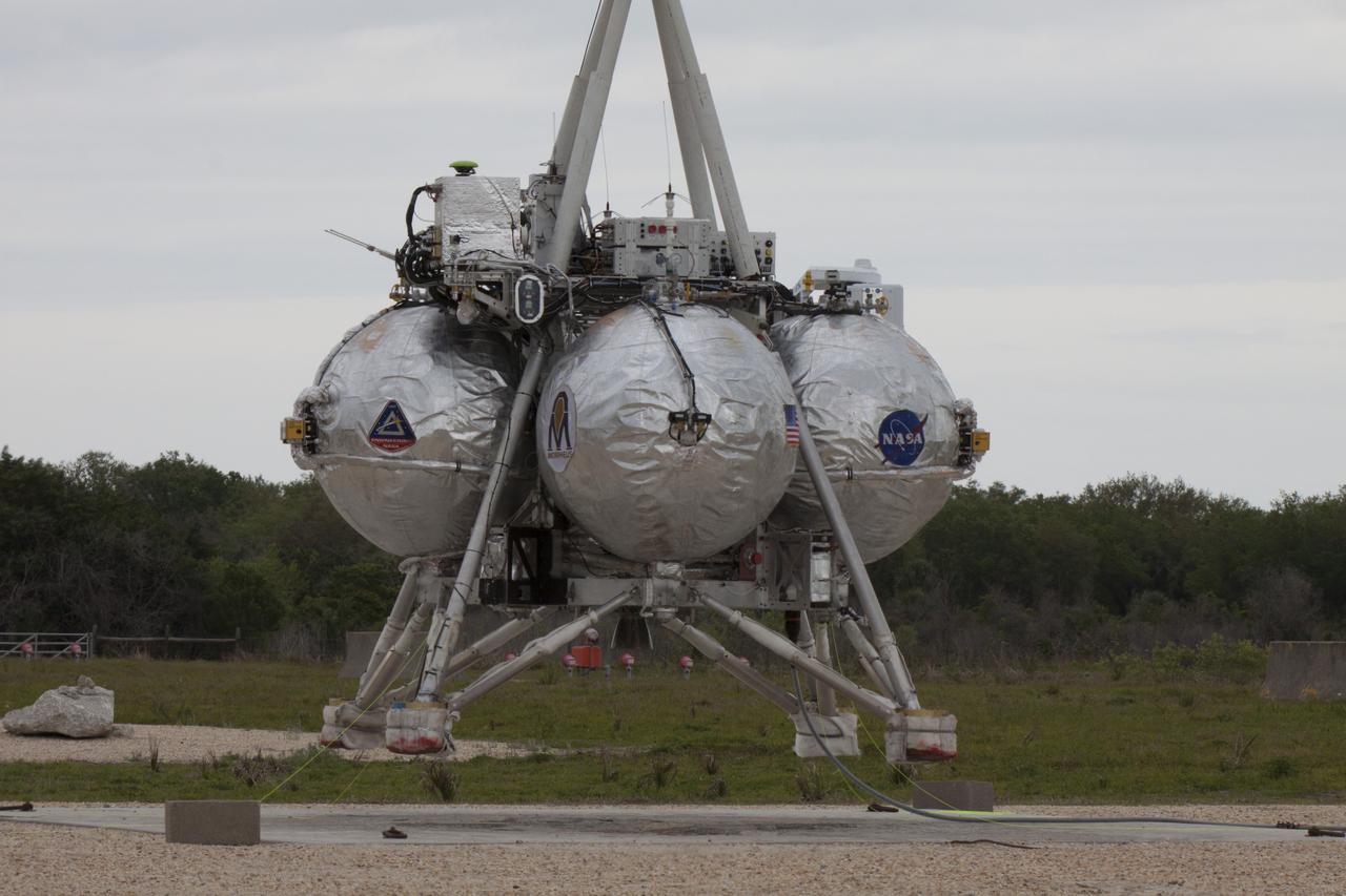 CAPE CANAVERAL, Fla. – NASA's Project Morpheus prototype lander is positioned near a new launch site at the north end of the Shuttle Landing Facility at NASA’s Kennedy Space Center in Florida for a tethered test. The test will be performed to verify the lander's recently installed autonomous landing and hazard avoidance technology, or ALHAT, sensors and integration system. The launch pad was moved to a different location at the landing facility to support the next phase of flight testing. Project Morpheus tests NASA’s ALHAT, and an engine that runs on liquid oxygen and methane, or green propellants, into a fully-operational lander that could deliver cargo to other planetary surfaces. The landing facility provides the lander with the kind of field necessary for realistic testing, complete with rocks, craters and hazards to avoid. Morpheus’ ALHAT payload allows it to navigate to clear landing sites amidst rocks, craters and other hazards during its descent. Project Morpheus is being managed under the Advanced Exploration Systems, or AES, Division in NASA’s Human Exploration and Operations Mission Directorate. The efforts in AES pioneer new approaches for rapidly developing prototype systems, demonstrating key capabilities and validating operational concepts for future human missions beyond Earth orbit. For more information on Project Morpheus, visit http://morpheuslander.jsc.nasa.gov/. Photo credit: NASA/Glenn Benson