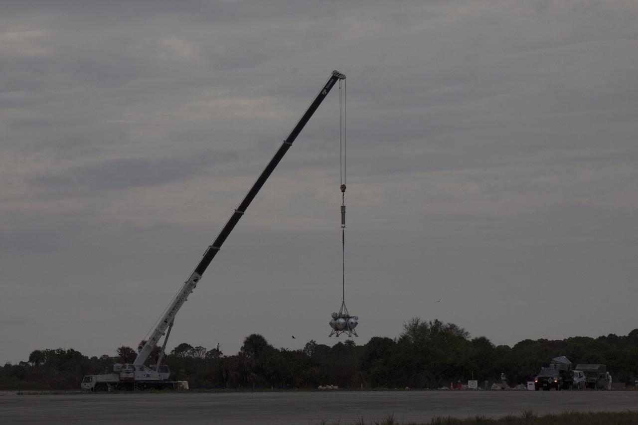 CAPE CANAVERAL, Fla. – NASA's Project Morpheus prototype lander is lifted by crane for a tethered test near a new launch site at the north end of the Shuttle Landing Facility at NASA’s Kennedy Space Center in Florida. The launch pad was moved to a different location at the landing facility to support the next phase of flight testing. The test was performed to verify the lander's recently installed autonomous landing and hazard avoidance technology, or ALHAT, sensors and integration systems. During the test, Morpheus was lifted by crane to 20 feet for an engine firing of about 74 seconds and then lowered to the ground. With the successful completion of the test, the Morpheus project team will begin preparing for the first free flight test with ALHAT. Morpheus tests NASA’s ALHAT, and an engine that runs on liquid oxygen and methane, or green propellants, into a fully-operational lander that could deliver cargo to other planetary surfaces. The landing facility provides the lander with the kind of field necessary for realistic testing, complete with rocks, craters and hazards to avoid. Morpheus’ ALHAT payload allows it to navigate to clear landing sites amidst rocks, craters and other hazards during its descent. Project Morpheus is being managed under the Advanced Exploration Systems, or AES, Division in NASA’s Human Exploration and Operations Mission Directorate. The efforts in AES pioneer new approaches for rapidly developing prototype systems, demonstrating key capabilities and validating operational concepts for future human missions beyond Earth orbit. For more information on Project Morpheus, visit http://morpheuslander.jsc.nasa.gov/. Photo credit: NASA/Glenn Benson