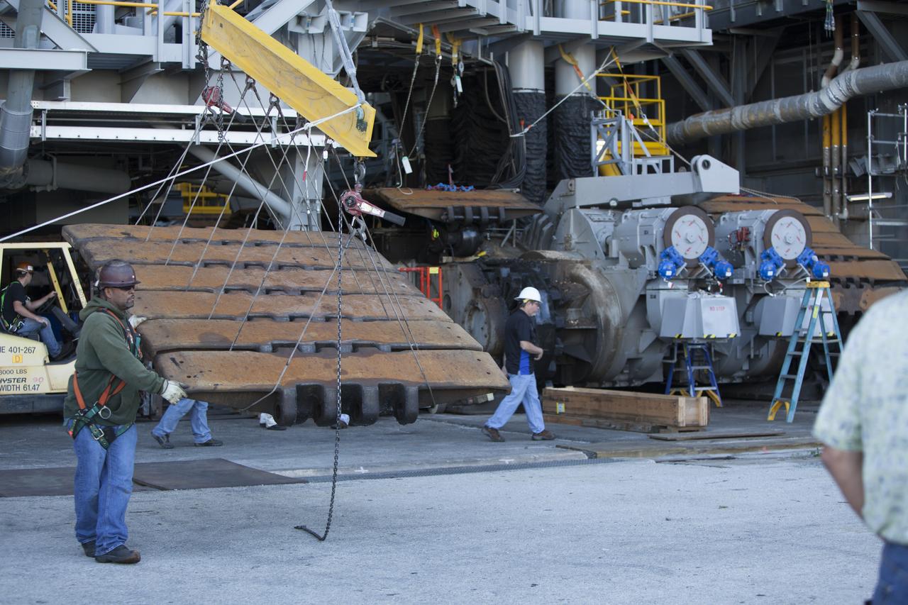 CAPE CANAVERAL, Fla. – Inside the Vehicle Assembly Building at NASA’s Kennedy Space Center in Florida, ground support technicians assist as a crane lifts a portion of the treads on the C truck of crawler-transporter 2, or CT-2, away from the vehicle. The treads are being removed in order to gain access to remove the gear boxes. Work continues in high bay 2 to upgrade CT-2. The modifications are designed to ensure CT-2’s ability to transport launch vehicles currently in development, such as the agency’s Space Launch System, to the launch pad. The Ground Systems Development and Operations Program office at Kennedy is overseeing the upgrades. For more than 45 years the crawler-transporters were used to transport the mobile launcher platform and the Apollo-Saturn V rockets and, later, space shuttles to Launch Pads 39A and B. For more information, visit: http://www.nasa.gov/exploration/systems/ground/crawler-transporter. Photo credit: NASA/Dimitri Gerondidakis