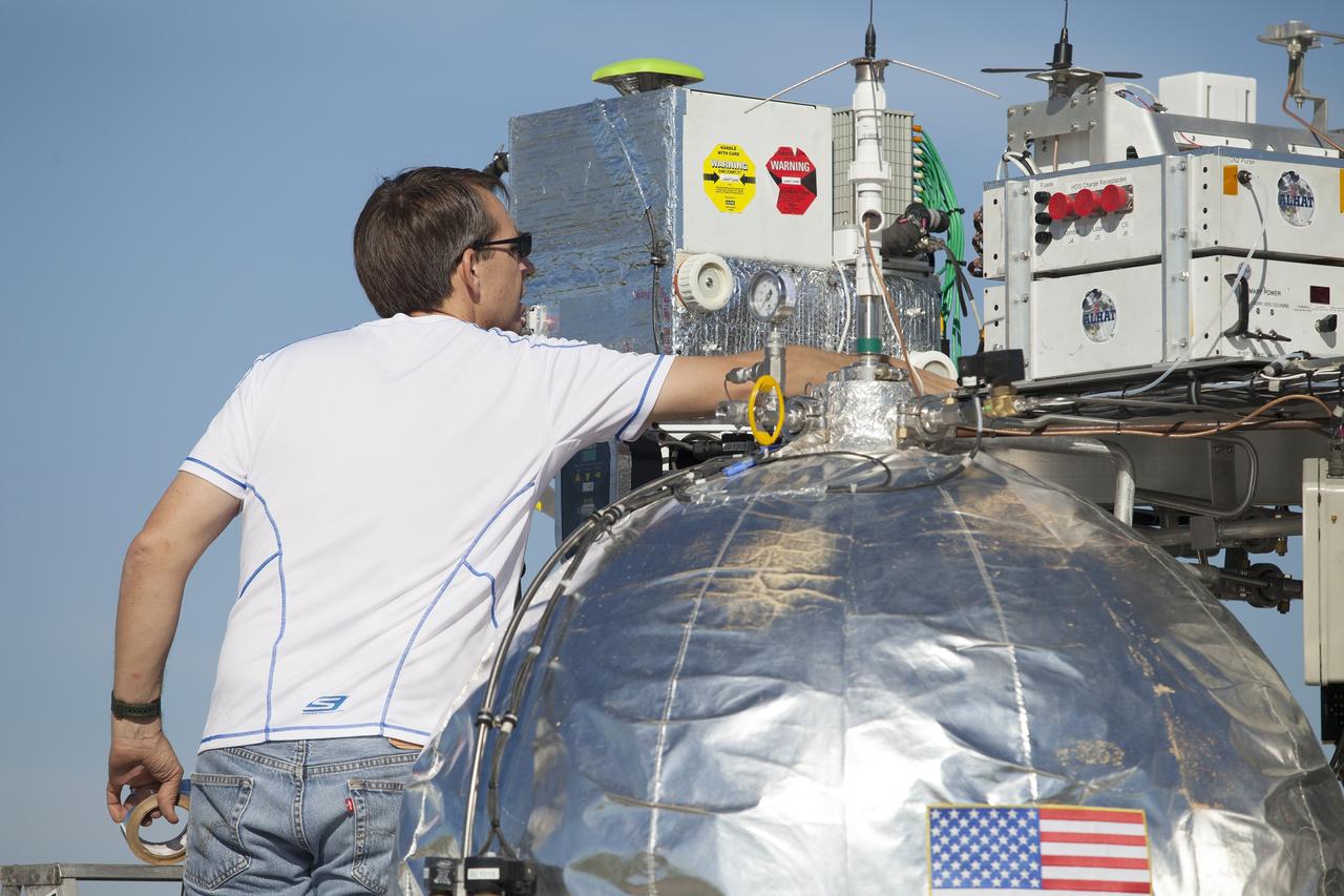 CAPE CANAVERAL, Fla. – An engineer helps prepare NASA's Project Morpheus prototype lander for a free flight test at a new launch site at the north end of the Shuttle Landing Facility at NASA’s Kennedy Space Center in Florida. The 96-second test began at 4:21 p.m. EDT with the Morpheus lander launching from the ground over the flame trench and ascending more than 800 feet at a peak speed of 36 mph. The vehicle with its recently installed autonomous landing and hazard avoidance technology, or ALHAT, sensors surveyed the hazard field to determine safe landing sites. Morpheus then flew forward and downward covering 1,300 feet while performing a 78-foot divert to simulate a hazard avoidance maneuver. The lander descended and landed on a dedicated pad inside the ALHAT field. Project Morpheus tests NASA’s ALHAT, and an engine that runs on liquid oxygen and methane, or green propellants, into a fully-operational lander that could deliver cargo to other planetary surfaces. The landing facility provides the lander with the kind of field necessary for realistic testing, complete with rocks, craters and hazards to avoid. Morpheus’ ALHAT payload allows it to navigate to clear landing sites amidst rocks, craters and other hazards during its descent. Project Morpheus is being managed under the Advanced Exploration Systems, or AES, Division in NASA’s Human Exploration and Operations Mission Directorate. The efforts in AES pioneer new approaches for rapidly developing prototype systems, demonstrating key capabilities and validating operational concepts for future human missions beyond Earth orbit. For more information on Project Morpheus, visit http://morpheuslander.jsc.nasa.gov/. Photo credit: NASA/Frankie Martin