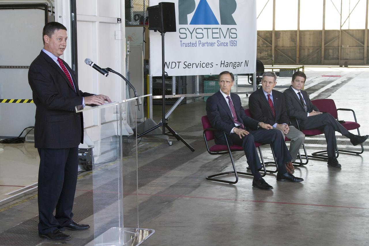 CAPE CANAVERAL, Fla. – Tony Corak, manager of nondestructive testing services for PaR Systems Inc., speaks during an Open House event at Hangar N at Cape Canaveral Air Force Station in Florida, to celebrate the one-year anniversary of a partnership with NASA Kennedy Space Center. Under a 15-year lease agreement, PaR Systems is utilizing Hangar N and its unique nondestructive testing equipment. To Corak's right is Brian Behm, president, aerospace robotics, PaR Systems Inc., Kennedy Center Director Bob Cabana, and Robert Salonen, business development director with the Economic Development Commission of Florida's Space Coast.    The partnership agreement was established by Kennedy's Center Planning and Development Directorate. The agreement is just one example of the types of partnerships that Kennedy is seeking to create a multi-user spaceport.  Photo credit: NASA/Cory Huston