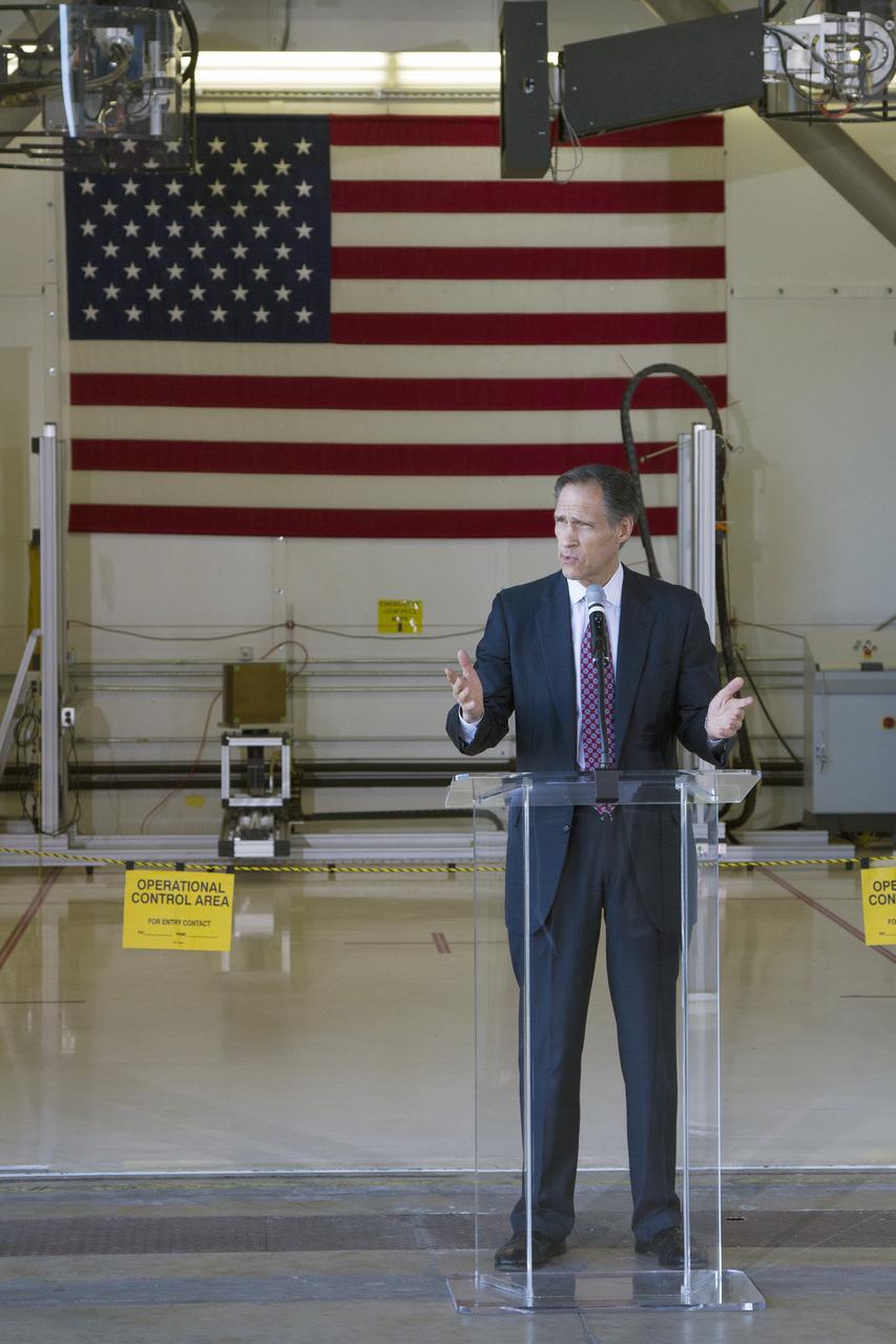 CAPE CANAVERAL, Fla. – Brian Behm, president, aerospace robotics, PaR Systems Inc., speaks during an Open House event at Hangar N at Cape Canaveral Air Force Station in Florida, to celebrate the one-year anniversary of a partnership with NASA Kennedy Space Center. Under a 15-year lease, PaR Systems is utilizing Hangar N and its unique nondestructive testing equipment. Behind Behm is the robotic inspection cell that contains an automated X-ray system once used to scan the aft skirts of the solid rocket boosters for the space shuttle.    The partnership agreement was established by Kennedy's Center Planning and Development Directorate. The agreement is just one example of the types of partnerships that Kennedy is seeking to create a multi-user spaceport.  Photo credit: NASA/Cory Huston