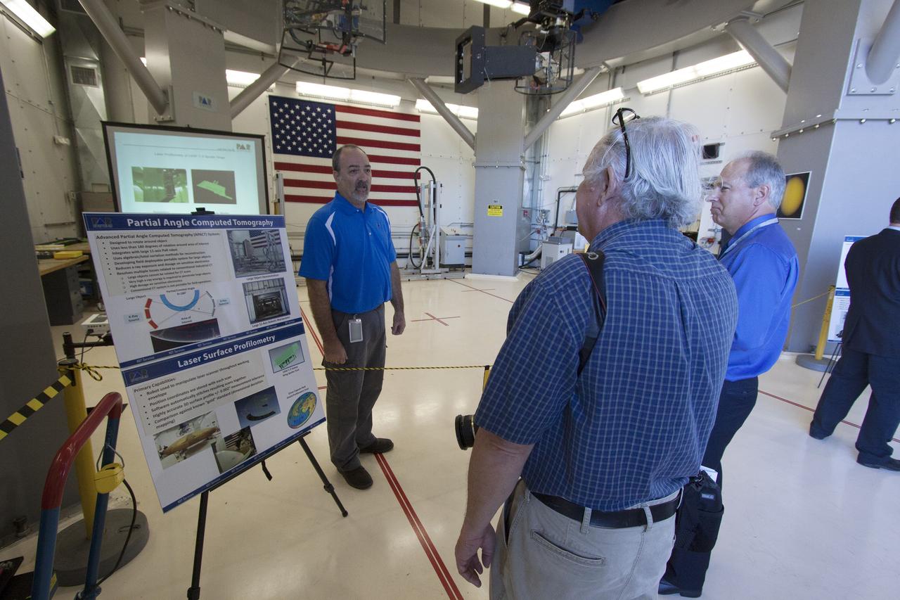 CAPE CANAVERAL, Fla. – Paul Vona, operations engineer, NDT Services, with PaR Systems Inc., talks with members of the media about the automated X-ray system in the robotic inspection cell at Hangar N at Cape Canaveral Air Force Station in Florida. PaR Systems held an Open House to celebrate the one-year anniversary of a lease agreement with Kennedy. Under a 15-year lease, PaR Systems is utilizing Hangar N and its unique nondestructive testing equipment.      The partnership agreement was established by Kennedy's Center Planning and Development Directorate. The agreement is just one example of the types of partnerships that Kennedy is seeking to create a multi-user spaceport.  Photo credit: NASA/Cory Huston