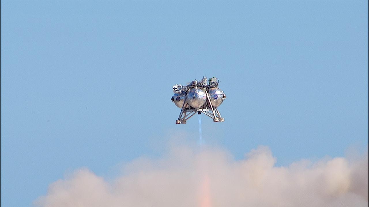 CAPE CANAVERAL, Fla. – NASA's Project Morpheus prototype lander soars high during a free flight test at the north end of the Shuttle Landing Facility at NASA's Kennedy Space Center in Florida. The 96-second test began at 4:21 p.m. EDT with the Morpheus lander launching from the ground over the flame trench at a new launch site and ascending more than 800 feet at a peak speed of 36 mph. The vehicle with its recently installed autonomous landing and hazard avoidance technology, or ALHAT, sensors surveyed the hazard field to determine safe landing sites. Morpheus then flew forward and downward covering 1,300 feet while performing a 78-foot divert to simulate a hazard avoidance maneuver. The lander descended and landed on a dedicated pad inside the ALHAT field. Project Morpheus tests NASA’s ALHAT, and an engine that runs on liquid oxygen and methane, or green propellants, into a fully-operational lander that could deliver cargo to other planetary surfaces.    The landing facility provides the lander with the kind of field necessary for realistic testing, complete with rocks, craters and hazards to avoid. Morpheus’ ALHAT payload allows it to navigate to clear landing sites amidst rocks, craters and other hazards during its descent. Project Morpheus is being managed under the Advanced Exploration Systems, or AES, Division in NASA’s Human Exploration and Operations Mission Directorate. The efforts in AES pioneer new approaches for rapidly developing prototype systems, demonstrating key capabilities and validating operational concepts for future human missions beyond Earth orbit. For more information on Project Morpheus, visit http://morpheuslander.jsc.nasa.gov/.  Photo credit: NASA/Frankie Martin