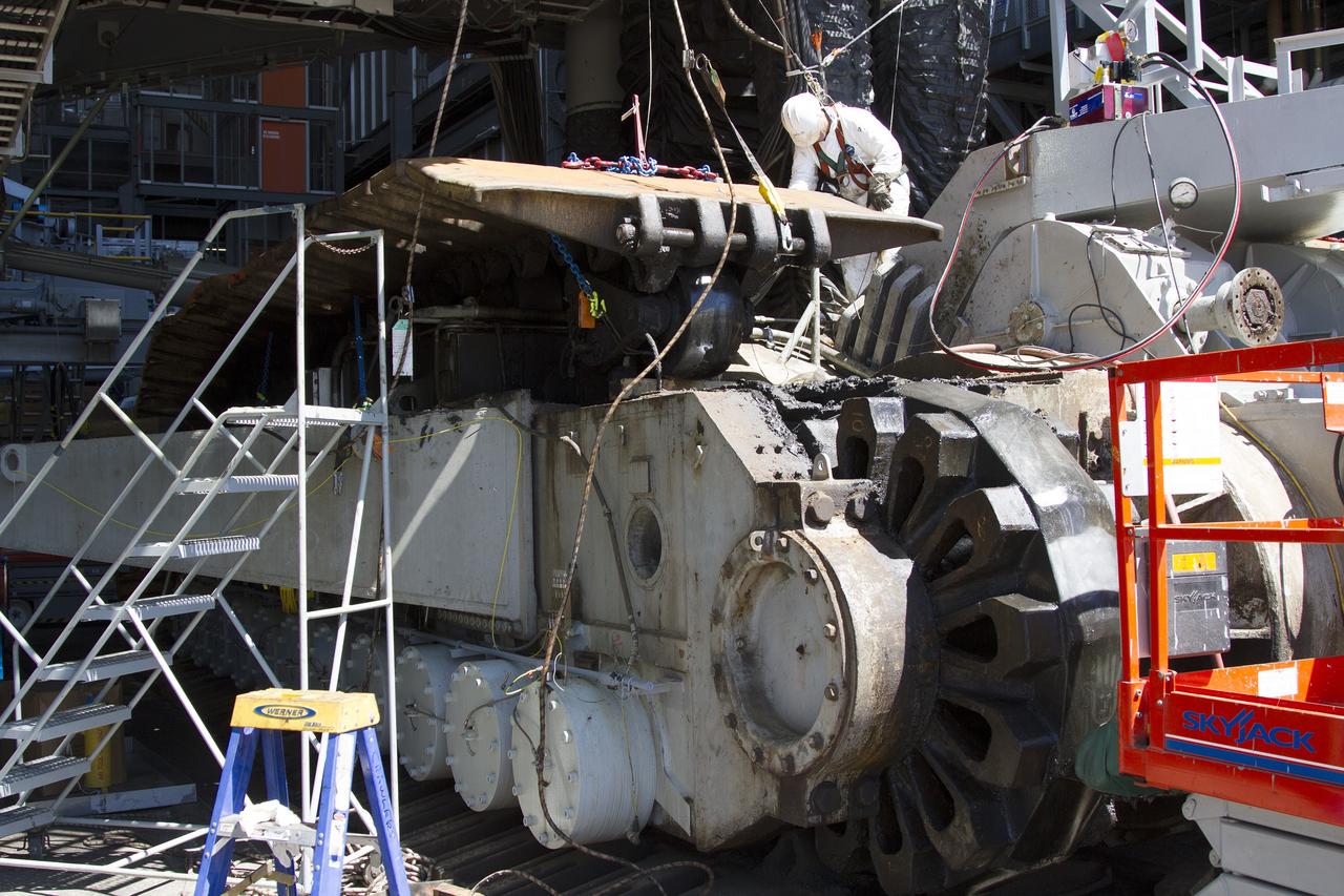 CAPE CANAVERAL, Fla. – Inside the Vehicle Assembly Building at NASA’s Kennedy Space Center in Florida, a ground support technician assists as a crane lifts up a section of the treads on the C truck of crawler-transporter 2, or CT-2. The treads are being removed in order to gain access to remove the gear boxes.    Work continues in high bay 2 to upgrade CT-2. The modifications are designed to ensure CT-2’s ability to transport launch vehicles currently in development, such as the agency’s Space Launch System, to the launch pad. The Ground Systems Development and Operations Program office at Kennedy is overseeing the upgrades. For more than 45 years the crawler-transporters were used to transport the mobile launcher platform and the Apollo-Saturn V rockets and, later, space shuttles to Launch Pads 39A and B. For more information, visit: http://www.nasa.gov/exploration/systems/ground/crawler-transporter. Photo credit: NASA/Cory Huston