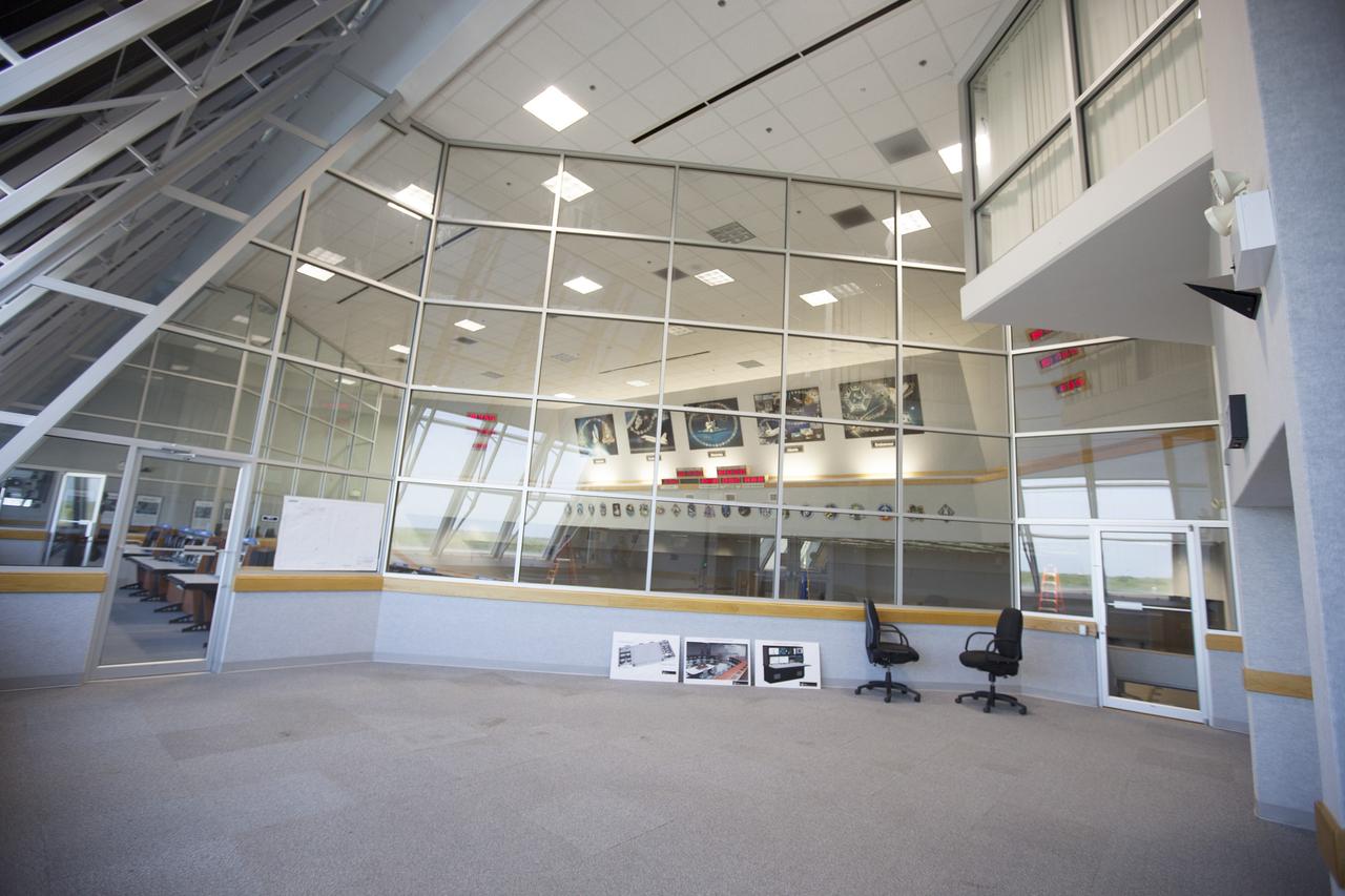 CAPE CANAVERAL, Fla. – Progress on modifications to Firing Room 4 in the Launch Control Center at NASA's Kennedy Space Center in Florida can be viewed through one of two glass-enclosed observation rooms. The Ground Systems Development and Operations Program is overseeing efforts to create a new firing room based on a multi-user concept that will support NASA and commercial launch needs. The main floor consoles, cabling and wires below the floor and ceiling tiles above have been removed. Sub flooring has been installed and the room is marked off to create four separate rooms on the main floor. In view along the soffit are space shuttle launch plaques for 21 missions launched from Firing Room 4. The design of Firing Room 4 will incorporate five control room areas that are flexible to meet current and future NASA and commercial user requirements. The equipment and most of the consoles from Firing Room 4 were moved to Firing Room 2 for possible future reuse. Photo credit: NASA/Ben Smegelsky