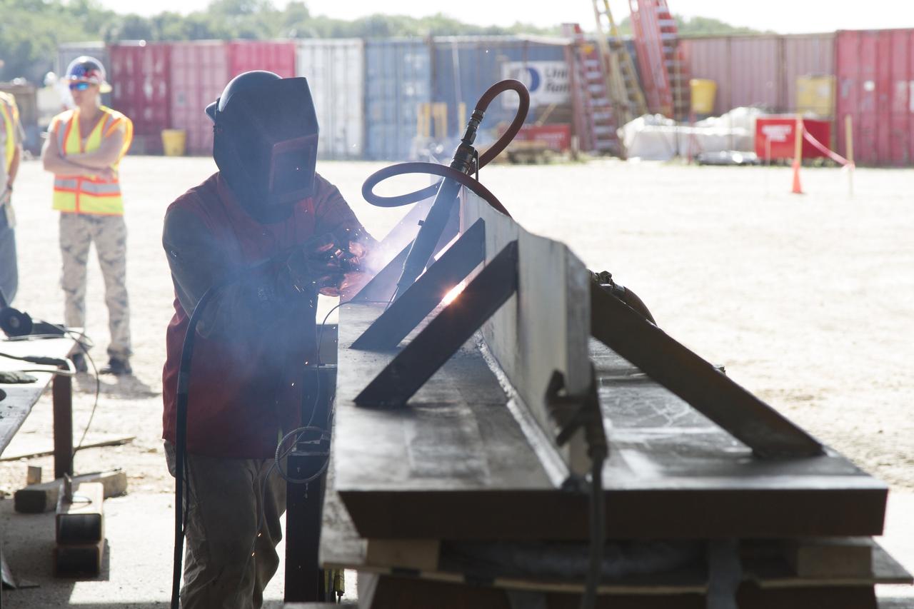 CAPE CANAVERAL, Fla. – Modifications continue on the Mobile Launcher, or ML, at the Mobile Launcher Park Site at NASA’s Kennedy Space Center in Florida. A construction worker welds a metal beam that will be attached to the ML.    In 2013, the agency awarded a contract to J.P. Donovan Construction Inc. of Rockledge, Fla., to modify the ML, which is one of the key elements of ground support equipment that is being upgraded by the Ground Systems Development and Operations Program office at Kennedy. The ML will carry the SLS rocket and Orion spacecraft to Launch Pad 39B for its first mission, Exploration Mission 1, in 2017. Photo credit: NASA/Cory Huston