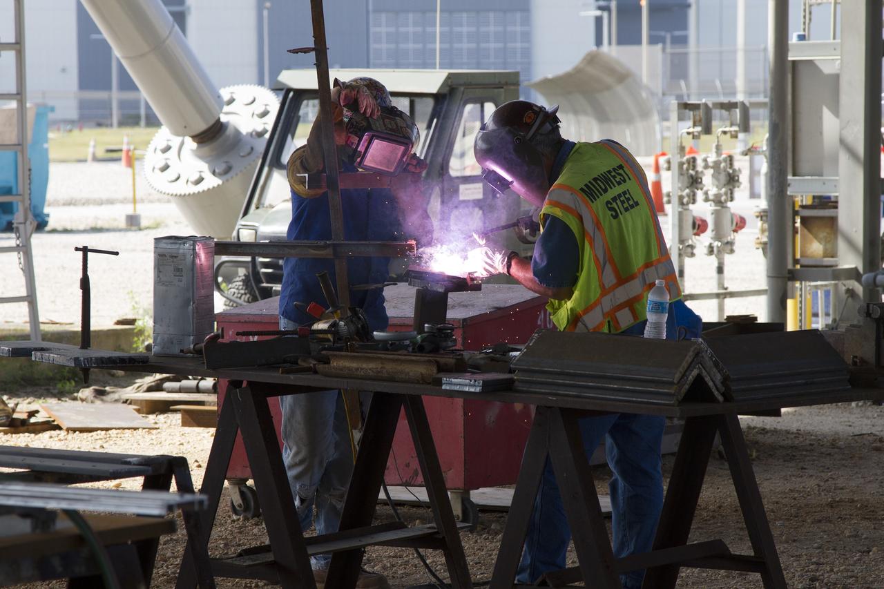 CAPE CANAVERAL, Fla. – Modifications continue on the Mobile Launcher, or ML, at the Mobile Launcher Park Site at NASA’s Kennedy Space Center in Florida. Construction workers perform welding on a section of metal that will be attached to the ML.    In 2013, the agency awarded a contract to J.P. Donovan Construction Inc. of Rockledge, Fla., to modify the ML, which is one of the key elements of ground support equipment that is being upgraded by the Ground Systems Development and Operations Program office at Kennedy. The ML will carry the SLS rocket and Orion spacecraft to Launch Pad 39B for its first mission, Exploration Mission 1, in 2017. Photo credit: NASA/Cory Huston
