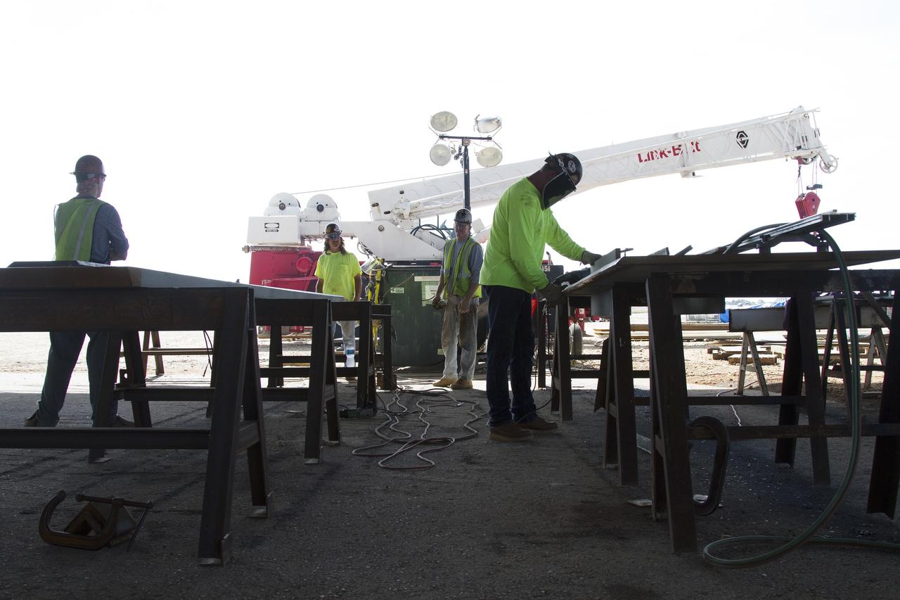 CAPE CANAVERAL, Fla. – Modifications continue on the Mobile Launcher, or ML, at the Mobile Launcher Park Site at NASA’s Kennedy Space Center in Florida. Construction workers prepare a section of metal for installation on the ML.    In 2013, the agency awarded a contract to J.P. Donovan Construction Inc. of Rockledge, Fla., to modify the ML, which is one of the key elements of ground support equipment that is being upgraded by the Ground Systems Development and Operations Program office at Kennedy. The ML will carry the SLS rocket and Orion spacecraft to Launch Pad 39B for its first mission, Exploration Mission 1, in 2017. Photo credit: NASA/Cory Huston