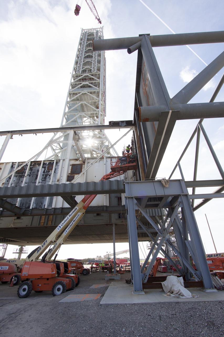 CAPE CANAVERAL, Fla. – Modifications continue on the Mobile Launcher, or ML, at the Mobile Launcher Park Site at NASA’s Kennedy Space Center in Florida. Construction workers on lifts perform welding work on a section of metal for installation on the ML.    In 2013, the agency awarded a contract to J.P. Donovan Construction Inc. of Rockledge, Fla., to modify the ML, which is one of the key elements of ground support equipment that is being upgraded by the Ground Systems Development and Operations Program office at Kennedy. The ML will carry the SLS rocket and Orion spacecraft to Launch Pad 39B for its first mission, Exploration Mission 1, in 2017. Photo credit: NASA/Cory Huston