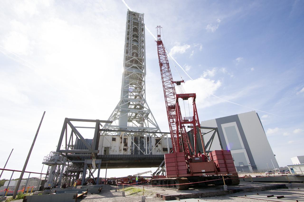 CAPE CANAVERAL, Fla. – Modifications continue on the Mobile Launcher, or ML, at the Mobile Launcher Park Site at NASA’s Kennedy Space Center in Florida. A large crane is situated next to the ML for lifting of heavy metal beams and other construction materials.     In 2013, the agency awarded a contract to J.P. Donovan Construction Inc. of Rockledge, Fla., to modify the ML, which is one of the key elements of ground support equipment that is being upgraded by the Ground Systems Development and Operations Program office at Kennedy. The ML will carry the SLS rocket and Orion spacecraft to Launch Pad 39B for its first mission, Exploration Mission 1, in 2017. Photo credit: NASA/Cory Huston