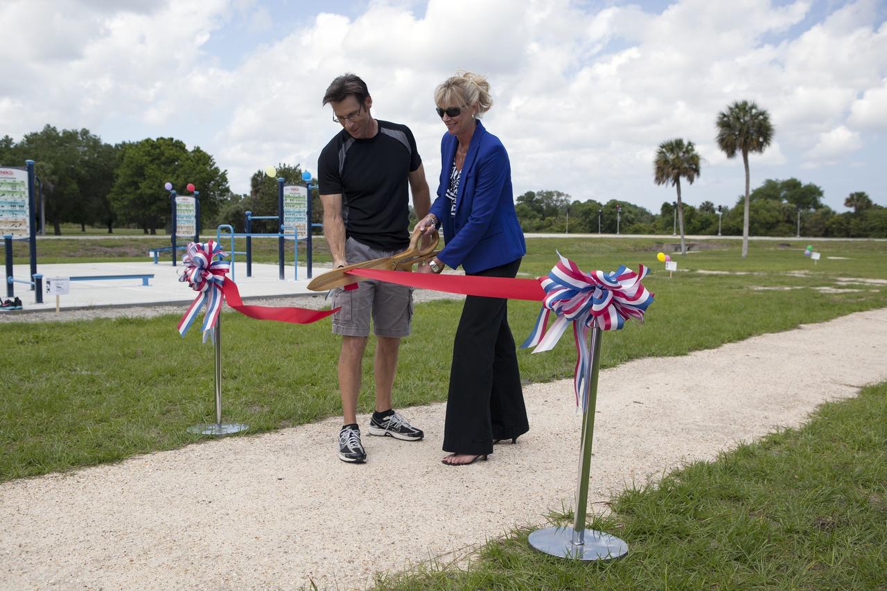 CAPE CANAVERAL, Fla. - Chuck Dovale, at left, deputy program manager of Launch Services, and Nancy Bray, director of Center Operations, cut a ribbon officially opening the new fitness trail next to the Space Station Processing Facility at NASA's Kennedy Space Center in Florida. The one-mile-long track will provide employees with a safe place off Kennedy's roadways to walk or run. The more than 6 tons of green waste removed to create the trail's footprint will be mulched and used for cover at Kennedy's landfill. Approximately 1,594 tons of crawler fines -- ground-up crawler rock removed from the crawlerway in the Launch Complex 39 area -- was used for the foundation of the trail. Fitness equipment has been ordered and will be installed on a concrete slab at the trail's west end. After the equipment has been installed, the slab will be coated to provide a rubberized exercise pad. At Kennedy Space Center, the health and safety of every employee is paramount. To learn more about Kennedy, visit http://www.nasa.gov/kennedy. Photo credit: NASA/Frankie Martin