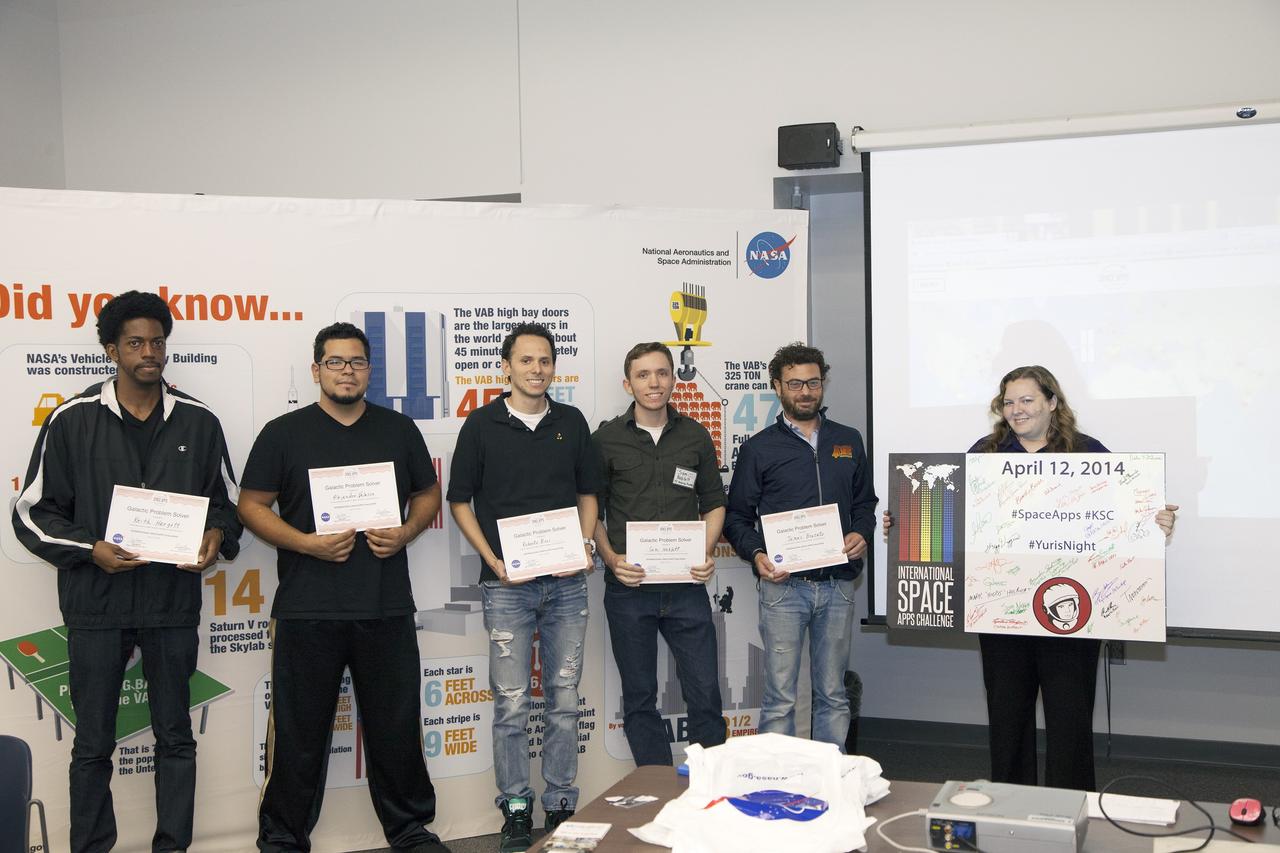 CAPE CANAVERAL, Fla. - Members of the winning teams in the International Space Apps Challenge display their Galactic Problem Solver certificates. From left are SpaceWear team members Keith Hargett and Alejandro Velasco, and Astronaut Resource Managing System team members Roberto Ricci, Sam Neblett, and James Brucato. Caley Burke, the NASA event organizer lead, is at right.      Kennedy Space Center hosted one of the over 90 locations around the world where participants congregated for the attempt to design innovative solutions for global challenges over a 48-hour period. This year's development marathon focused on five NASA mission areas: Asteroids, Earth Watch, Human Spaceflight, Robotics, and Technology in Space. Three of this year’s challenges were developed by KSC employees: Space Wearables: Fashion Designer to Astronauts, Growing Food for a Martian Table, and Asteroid Prospector. The winners selected in 2014 at Kennedy were Astronaut Resource Managing System, or ARMS, for Best Use of Data and SpaceWear for Best Use of Hardware. ARMS also took the People's Choice Award. For more information, visit https://2014.spaceappschallenge.org.  Photo credit: NASA/Daniel Casper