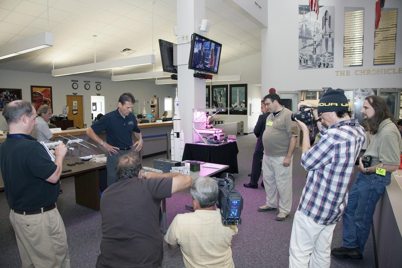 CAPE CANAVERAL, Fla. - Scott Higginbotham, center, mission manager for ELaNa V, discusses the concepts behind the design and deployment of the CubeSats flying on the ELaNa V mission with media representatives in the NASA Newsroom at Kennedy Space Center in Florida, using models of the Poly-Picosatellite Orbital Deployer, or P-POD, and various CubeSat canisters.     NASA selected five small research satellites, or CubeSats, for the ELaNa V mission launching on SpaceX-3. Four P-PODs aboard the SpaceX Falcon 9 rocket will ferry them to space. The CubeSats were designed by three universities and the agency's Ames Research Center in California. Launch is scheduled at about 4:58 p.m. EDT April 14. The SpaceX-3 mission, carrying almost 2.5 tons of supplies, technology and science experiments, is the third of 12 flights under NASA's Commercial Resupply Services contract to resupply the orbiting laboratory. For more information about NASA's CubeSat Launch Initiative, visit http://go.nasa.gov/CubeSat_initiative. Photo credit: NASA/Glenn Benson
