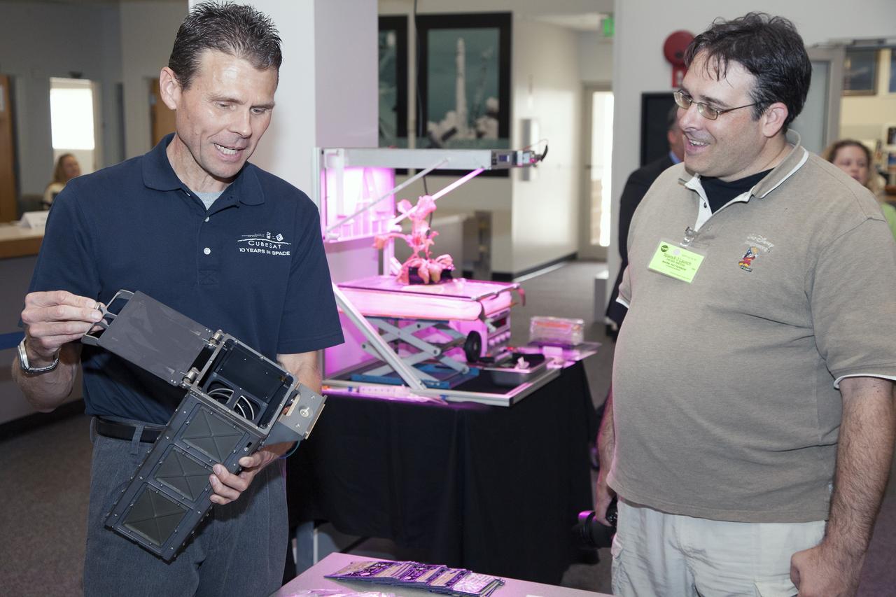 CAPE CANAVERAL, Fla. - Scott Higginbotham, left, mission manager for ELaNa V, demonstrates the concepts behind the design and deployment of the CubeSats flying on the ELaNa V mission with a media representative in the NASA Newsroom at Kennedy Space Center in Florida, using a model of the Poly-Picosatellite Orbital Deployer, or P-POD.     NASA selected five small research satellites, or CubeSats, for the ELaNa V mission launching on SpaceX-3. Four P-PODs aboard the SpaceX Falcon 9 rocket will ferry them to space. The CubeSats were designed by three universities and the agency's Ames Research Center in California. Launch is scheduled at about 4:58 p.m. EDT April 14. The SpaceX-3 mission, carrying almost 2.5 tons of supplies, technology and science experiments, is the third of 12 flights under NASA's Commercial Resupply Services contract to resupply the orbiting laboratory. For more information about NASA's CubeSat Launch Initiative, visit http://go.nasa.gov/CubeSat_initiative. Photo credit: NASA/Glenn Benson