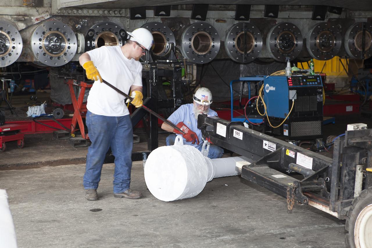 CAPE CANAVERAL, Fla. - Inside the Vehicle Assembly Building at NASA’s Kennedy Space Center in Florida, ground support technicians attach a roller bearing shaft to a forklift. The bearing is being prepared for insertion in the C truck of crawler-transporter 2, or CT-2. A section of the treads on the C truck were removed to allow access to the bearings.    Work continues in high bay 2 to upgrade CT-2. The modifications are designed to ensure CT-2’s ability to transport launch vehicles currently in development, such as the agency’s Space Launch System, to the launch pad. The Ground Systems Development and Operations Program office at Kennedy is overseeing the upgrades. For more than 45 years the crawler-transporters were used to transport the mobile launcher platform and the Apollo-Saturn V rockets and, later, space shuttles to Launch Pads 39A and B. For more information, visit: http://www.nasa.gov/exploration/systems/ground/crawler-transporter. Photo credit: NASA/Dimitri Gerondidakis