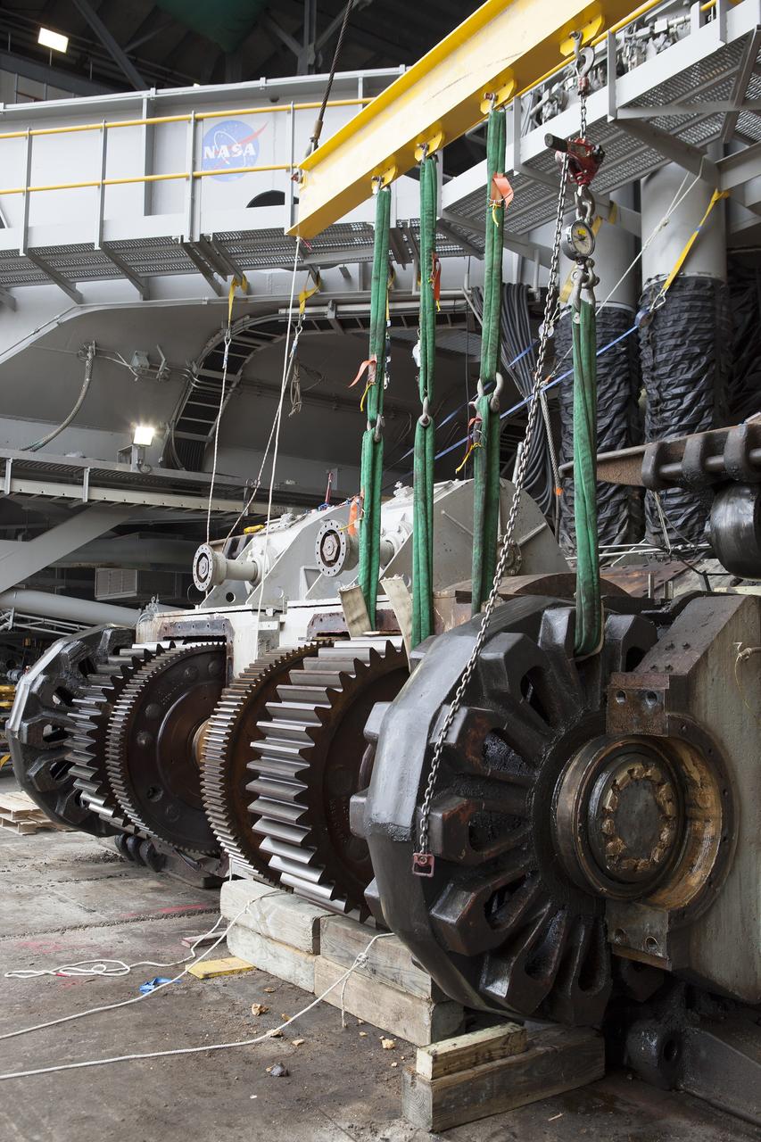 CAPE CANAVERAL, Fla. - Inside the Vehicle Assembly Building at NASA’s Kennedy Space Center in Florida, an overhead crane has been attached to a sprocket shaft assembly to remove it from the C truck of crawler-transporter 2, or CT-2. A section of the treads on the C truck were removed to allow access to the sprocket assemblies. The sprocket assemblies will be placed into shipping cradles on pallets and positioned on a flatbed trailer. The assemblies will be sent to a vendor for inspections and refurbishment.      Work continues in high bay 2 to upgrade CT-2. The modifications are designed to ensure CT-2’s ability to transport launch vehicles currently in development, such as the agency’s Space Launch System, to the launch pad. The Ground Systems Development and Operations Program office at Kennedy is overseeing the upgrades. For more than 45 years the crawler-transporters were used to transport the mobile launcher platform and the Apollo-Saturn V rockets and, later, space shuttles to Launch Pads 39A and B. For more information, visit: http://www.nasa.gov/exploration/systems/ground/crawler-transporter. Photo credit: NASA/Dimitri Gerondidakis