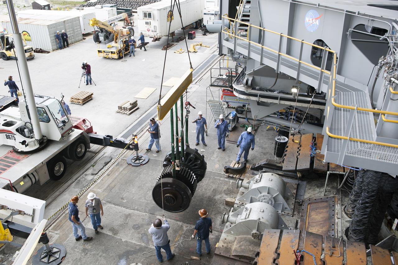 CAPE CANAVERAL, Fla. - Inside the Vehicle Assembly Building at NASA’s Kennedy Space Center in Florida, ground support technicians monitor the progress as an overhead crane lifts a sprocket shaft assembly away from the C truck of crawler-transporter 2, or CT-2. A section of the treads on the C truck were removed to allow access to the sprocket assemblies. The sprocket assemblies will be placed into shipping cradles on pallets and positioned on a flatbed trailer. The assemblies will be sent to a vendor for inspections and refurbishment.      Work continues in high bay 2 to upgrade CT-2. The modifications are designed to ensure CT-2’s ability to transport launch vehicles currently in development, such as the agency’s Space Launch System, to the launch pad. The Ground Systems Development and Operations Program office at Kennedy is overseeing the upgrades. For more than 45 years the crawler-transporters were used to transport the mobile launcher platform and the Apollo-Saturn V rockets and, later, space shuttles to Launch Pads 39A and B. For more information, visit: http://www.nasa.gov/exploration/systems/ground/crawler-transporter. Photo credit: NASA/Dimitri Gerondidakis