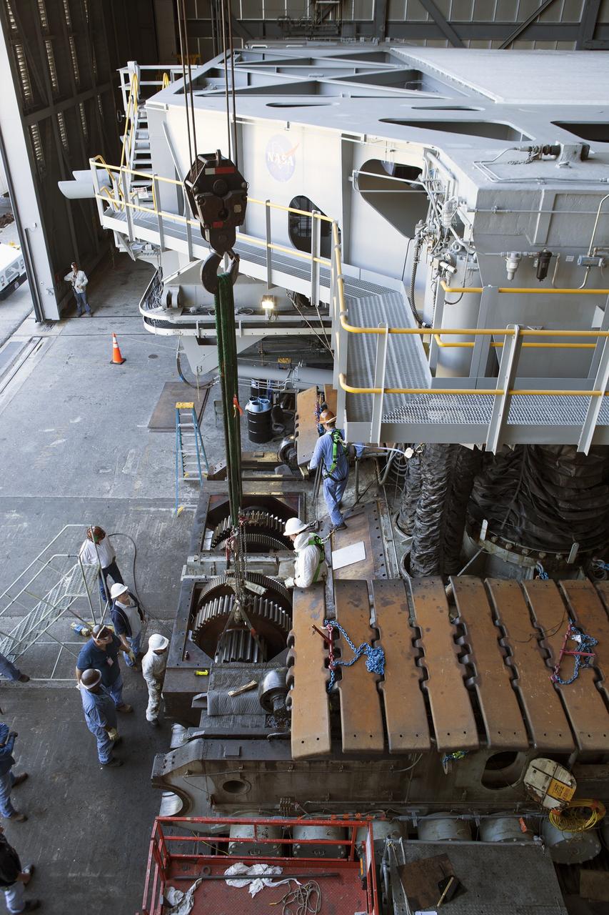 CAPE CANAVERAL, Fla. -- Inside the Vehicle Assembly Building at NASA’s Kennedy Space Center in Florida, ground support technicians prepare for removal of one of the sprocket shaft assemblies on the C truck of crawler-transporter 2, or CT-2. A section of the treads on the C truck were removed to allow access to the sprocket assemblies.    Work continues in high bay 2 to upgrade CT-2. The modifications are designed to ensure CT-2’s ability to transport launch vehicles currently in development, such as the agency’s Space Launch System, to the launch pad. The Ground Systems Development and Operations Program office at Kennedy is overseeing the upgrades. For more than 45 years the crawler-transporters were used to transport the mobile launcher platform and the Apollo-Saturn V rockets and, later, space shuttles to Launch Pads 39A and B. For more information, visit: http://www.nasa.gov/exploration/systems/ground/crawler-transporter. Photo credit: NASA/Dimitri Gerondidakis