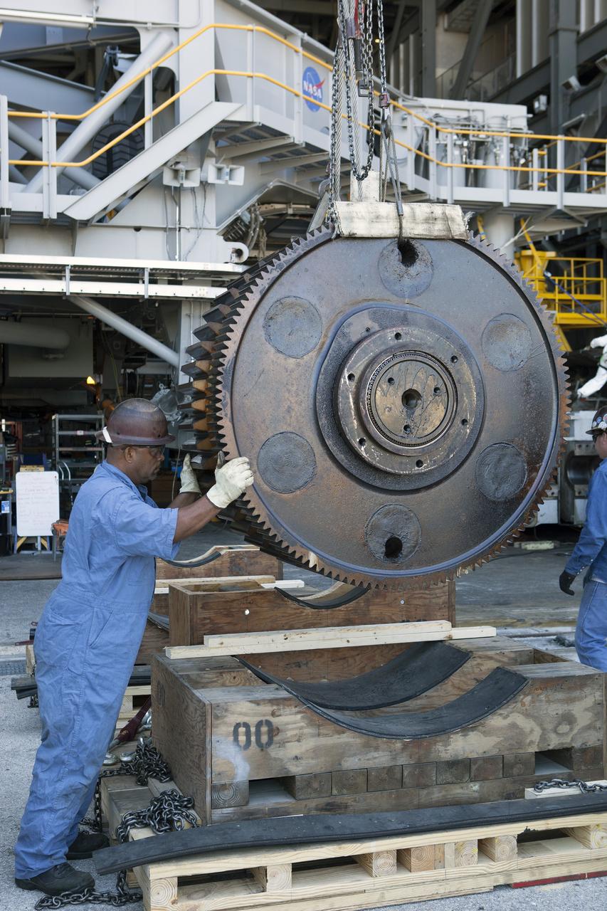 CAPE CANAVERAL, Fla. -- Inside the Vehicle Assembly Building at NASA’s Kennedy Space Center in Florida, a ground support technician helps position one of the sprocket shaft assemblies onto a cradle as an overhead crane lowers it down. The sprocket assembly was removed from the C truck of crawler-transporter 2, or CT-2. They will be placed into shipping cradles on pallets and positioned on a flatbed trailer. They will be sent to a vendor for inspections and refurbishment.    Work continues in high bay 2 to upgrade CT-2. The modifications are designed to ensure CT-2’s ability to transport launch vehicles currently in development, such as the agency’s Space Launch System, to the launch pad. The Ground Systems Development and Operations Program office at Kennedy is overseeing the upgrades. For more than 45 years the crawler-transporters were used to transport the mobile launcher platform and the Apollo-Saturn V rockets and, later, space shuttles to Launch Pads 39A and B. For more information, visit: http://www.nasa.gov/exploration/systems/ground/crawler-transporter. Photo credit: NASA/Dimitri Gerondidakis