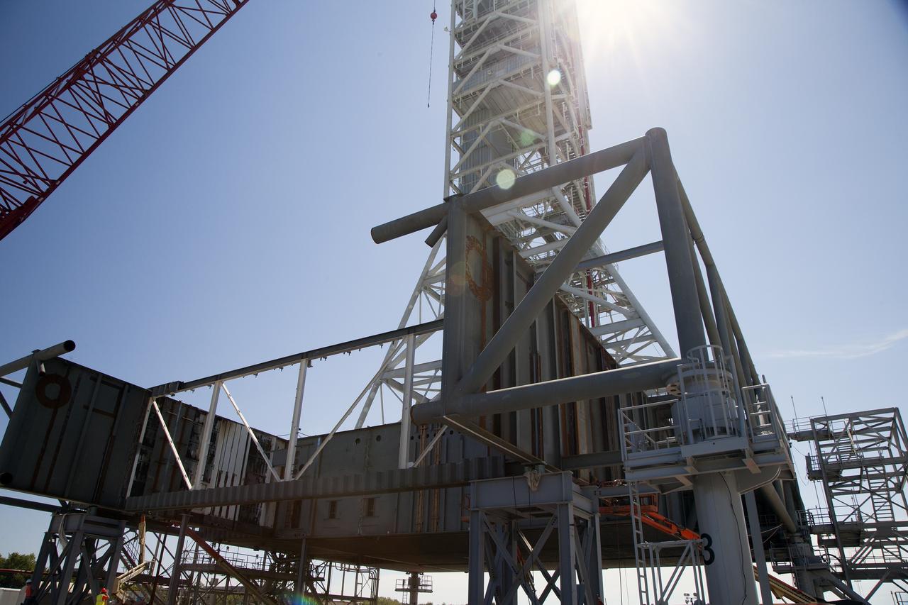 CAPE CANAVERAL, Fla. -- Modifications continue on the Mobile Launcher, or ML, at the Mobile Launcher Park Site at NASA’s Kennedy Space Center in Florida. Sections of the steel walls have been removed for welding work.     In 2013, the agency awarded a contract to J.P. Donovan Construction Inc. of Rockledge, Fla., to modify the ML, which is one of the key elements of ground support equipment that is being upgraded by the Ground Systems Development and Operations Program office at Kennedy. The ML will carry the SLS rocket and Orion spacecraft to Launch Pad 39B for its first mission, Exploration Mission 1, in 2017. Photo credit: NASA/Daniel Casper