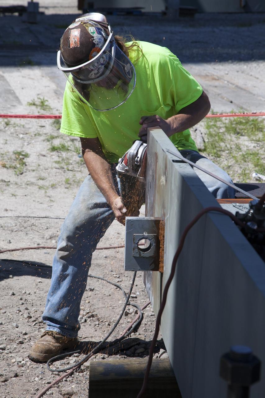 CAPE CANAVERAL, Fla. -- Modifications continue on the Mobile Launcher, or ML, at the Mobile Launcher Park Site at NASA’s Kennedy Space Center in Florida. A construction worker cuts a piece of steel to resize it for the exterior of the ML.     In 2013, the agency awarded a contract to J.P. Donovan Construction Inc. of Rockledge, Fla., to modify the ML, which is one of the key elements of ground support equipment that is being upgraded by the Ground Systems Development and Operations Program office at Kennedy. The ML will carry the SLS rocket and Orion spacecraft to Launch Pad 39B for its first mission, Exploration Mission 1, in 2017. Photo credit: NASA/Daniel Casper