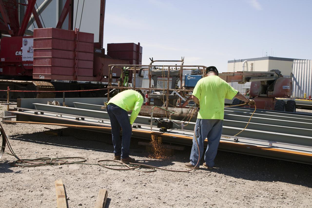 CAPE CANAVERAL, Fla. -- Modifications continue on the Mobile Launcher, or ML, at the Mobile Launcher Park Site at NASA’s Kennedy Space Center in Florida. Construction workers use an automated cutting tool to precisely trim a small section from one of the steel walls for the exterior of the ML.    In 2013, the agency awarded a contract to J.P. Donovan Construction Inc. of Rockledge, Fla., to modify the ML, which is one of the key elements of ground support equipment that is being upgraded by the Ground Systems Development and Operations Program office at Kennedy. The ML will carry the SLS rocket and Orion spacecraft to Launch Pad 39B for its first mission, Exploration Mission 1, in 2017. Photo credit: NASA/Daniel Casper